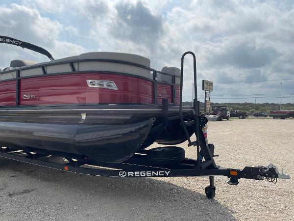 2023 Regency 250DL3 pontoon boat on trailer, parked outdoors under cloudy sky.