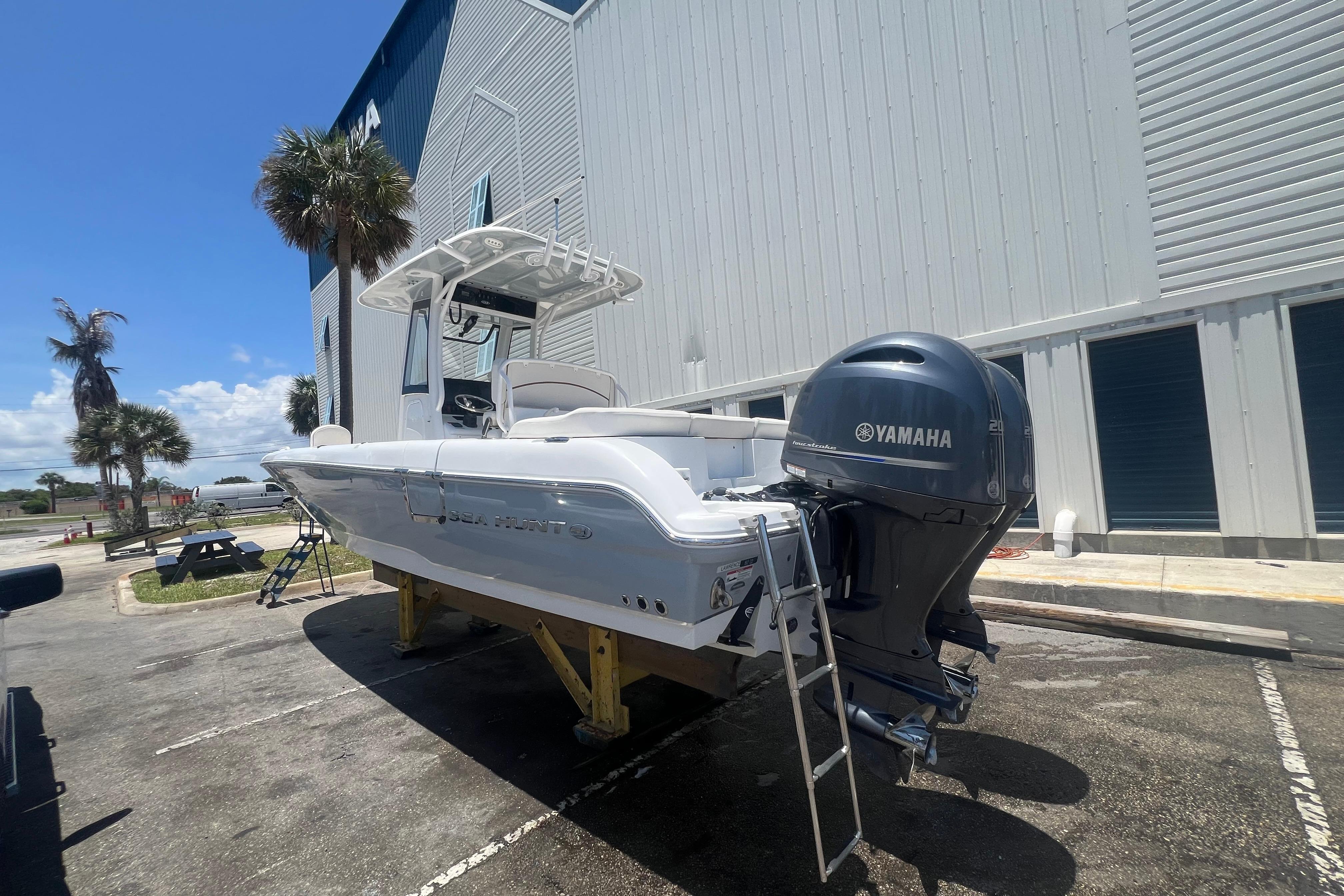 2022 Sea Hunt Escape 27 boat with Yamaha engine, parked outdoors near a building.