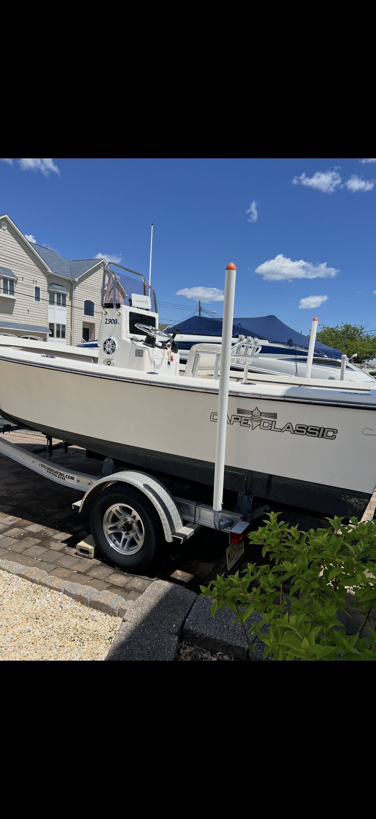 A white center console boat on a trailer, parked in a residential area.