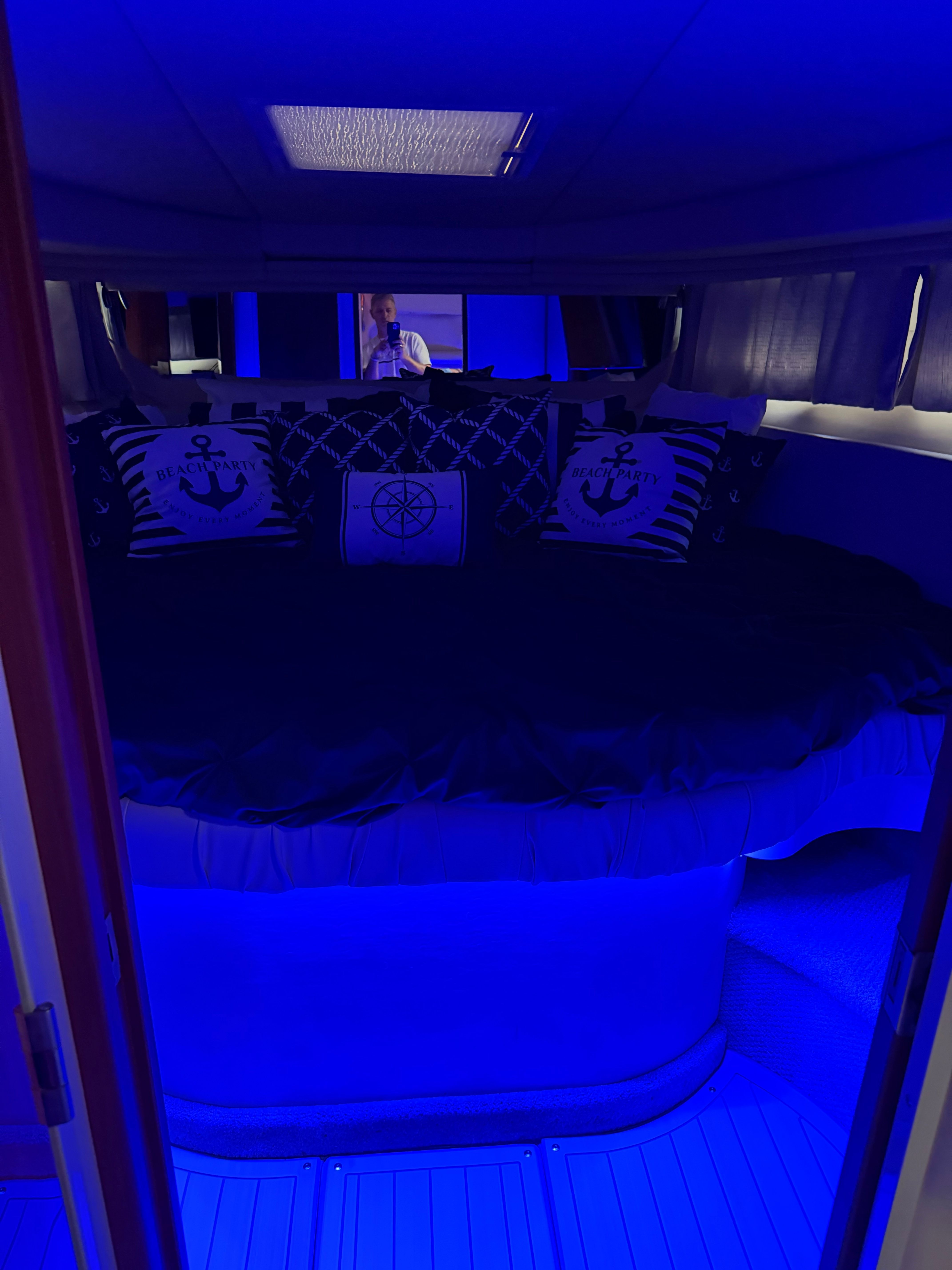 A cozy boat interior with blue lighting and nautical-themed pillows.