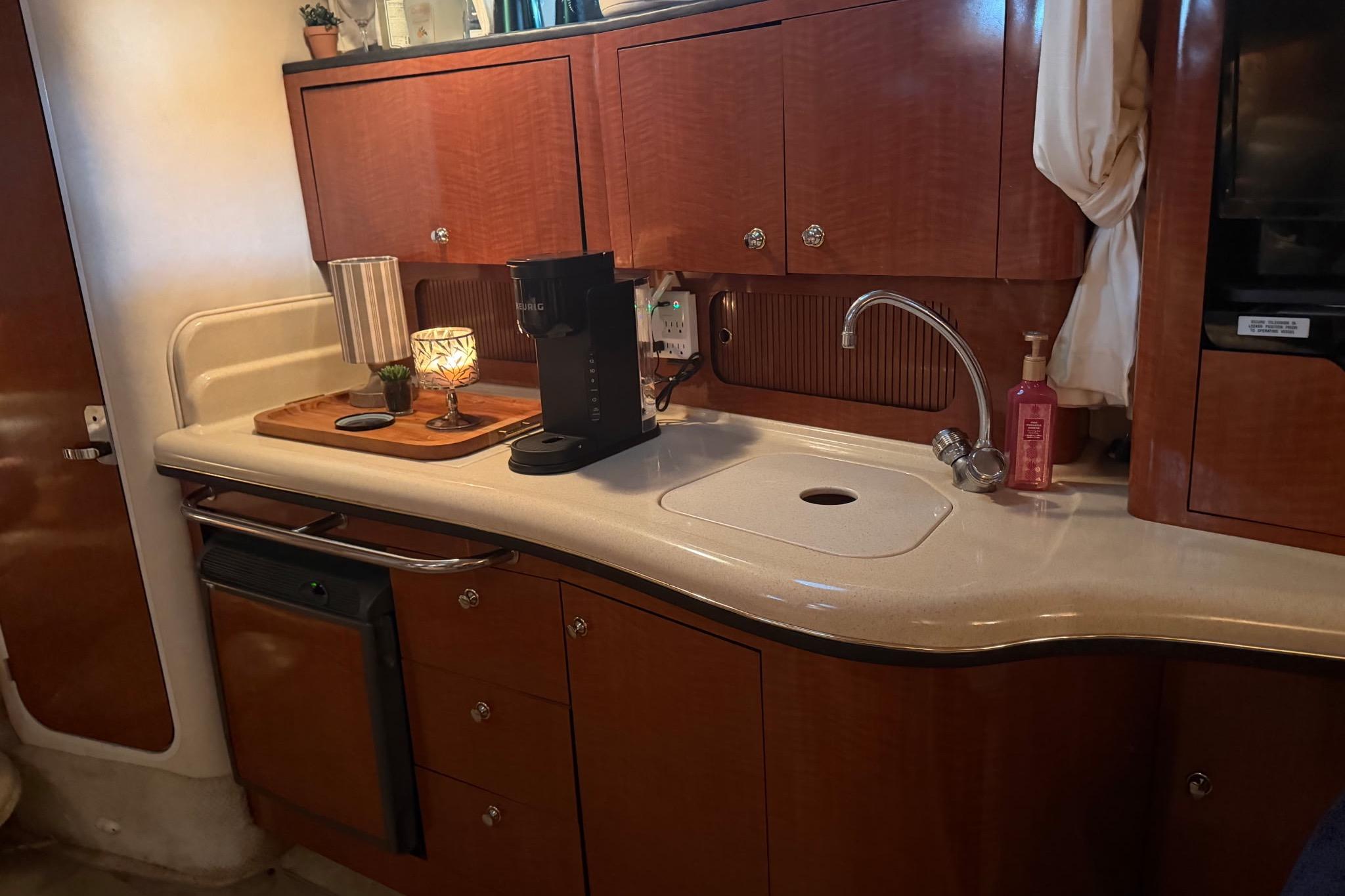 Interior of 2002 Sea Ray Sundancer 320 yacht kitchen with wooden cabinets and sink.