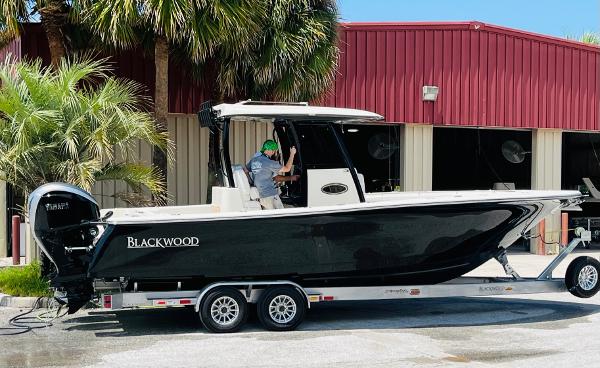 2024 Blackwood 290 boat on trailer in front of red building.