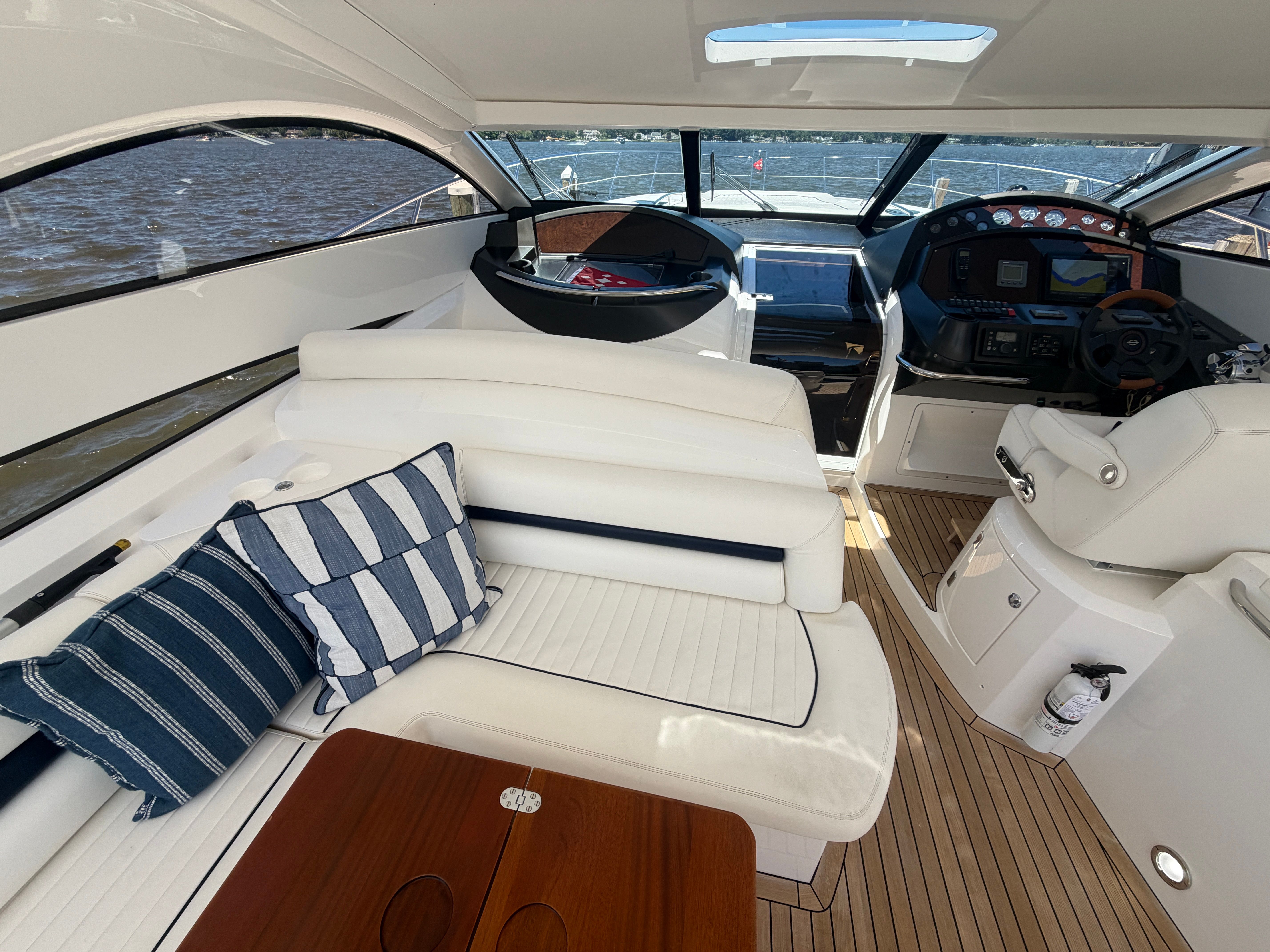 Interior of a Sunseeker Portofino 53 with white seating and wooden table, overlooking the water.