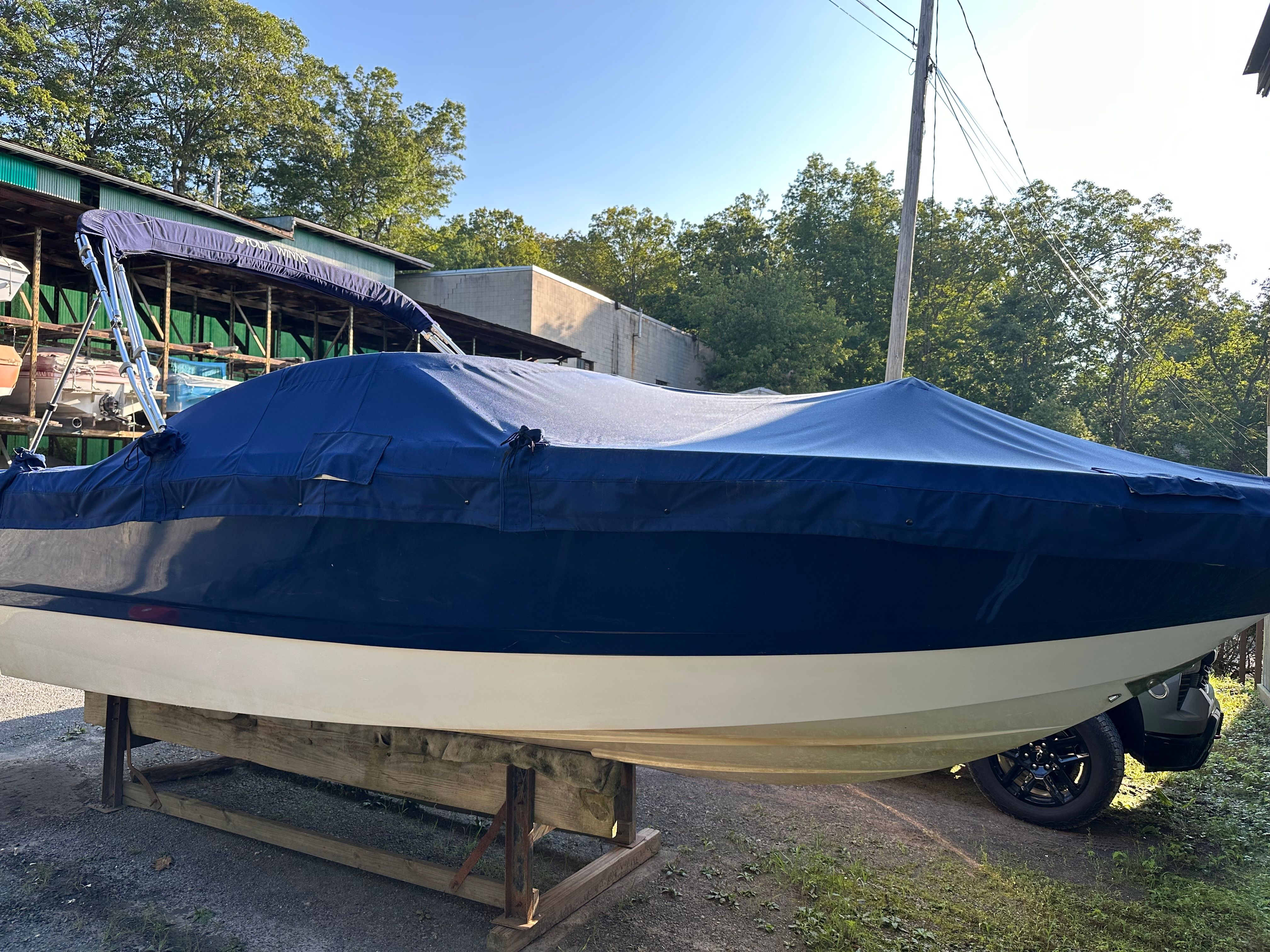 2012 Four Winns H210 boat with blue cover outdoors.