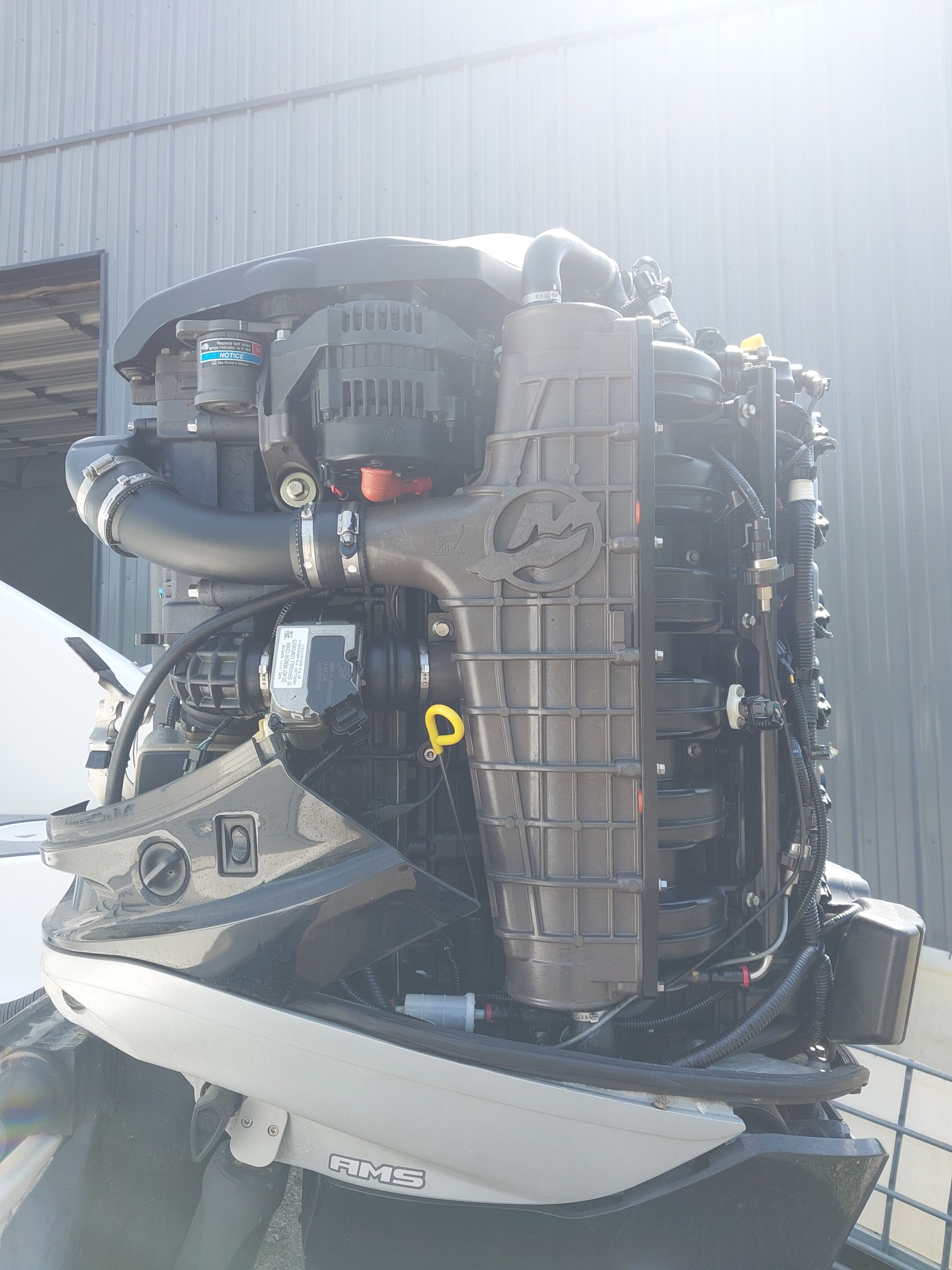 Close-up of an outboard motor on a boat, showing detailed components and hoses.