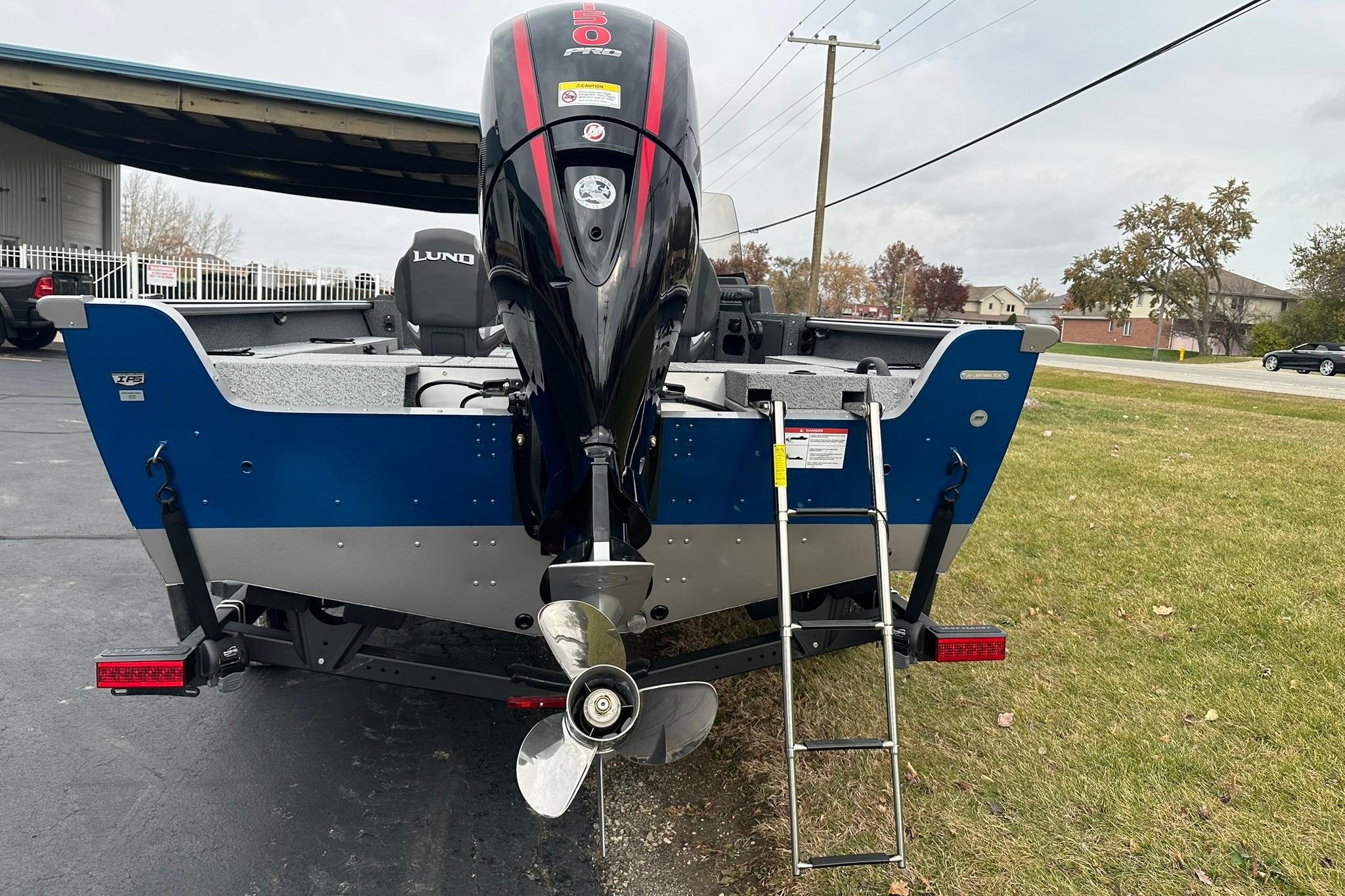 2026 Lund 1875 Impact XS SS boat with outboard motor and ladder on a trailer.