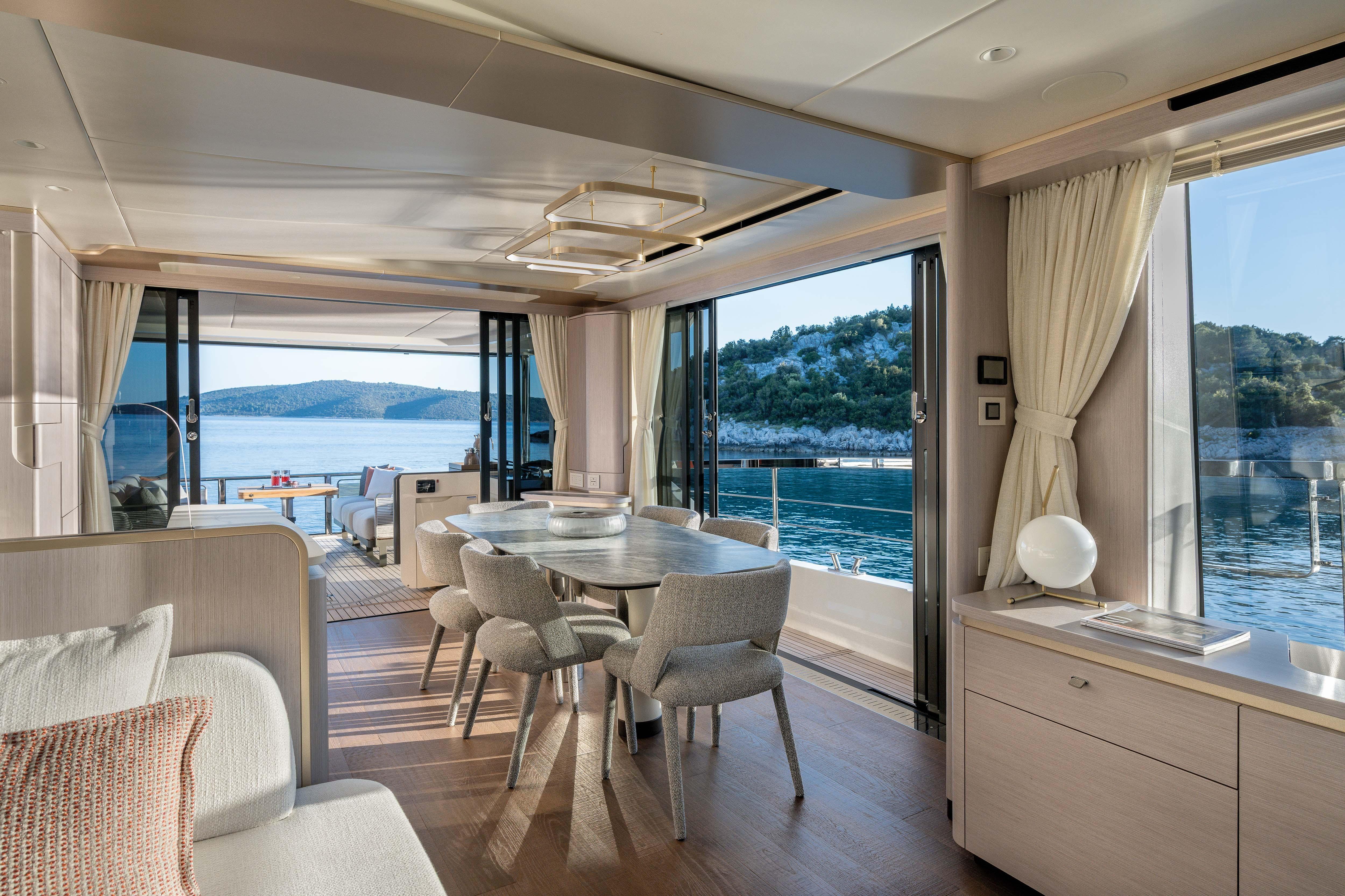 Interior of a luxury yacht with dining area and view of the water.