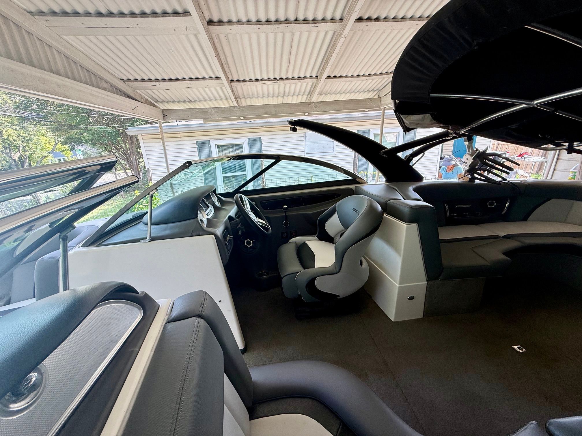 Interior of a 2012 Supra Launch 242 with gray and black seating under a covered area.