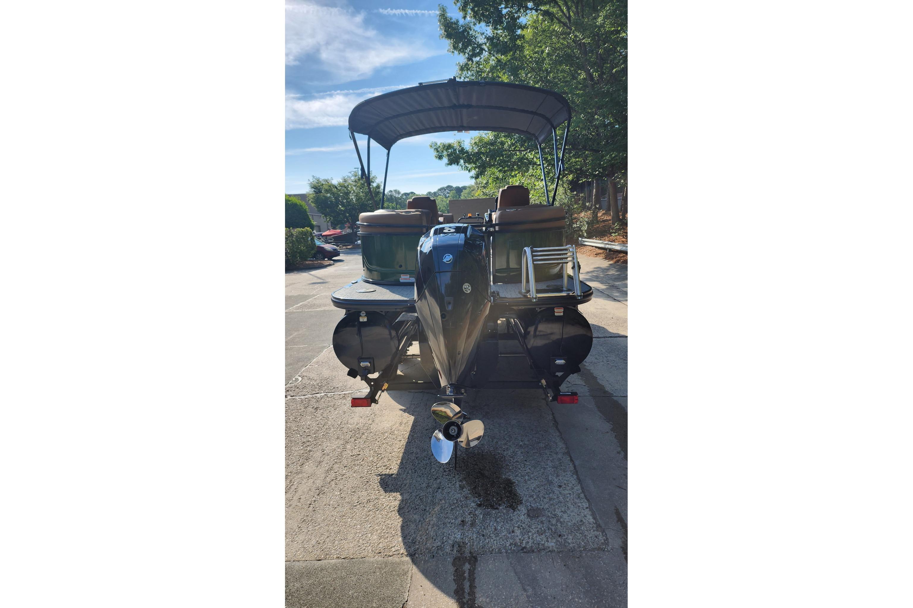 2026 Regency 230 DL pontoon boat with canopy, parked outdoors on a sunny day.