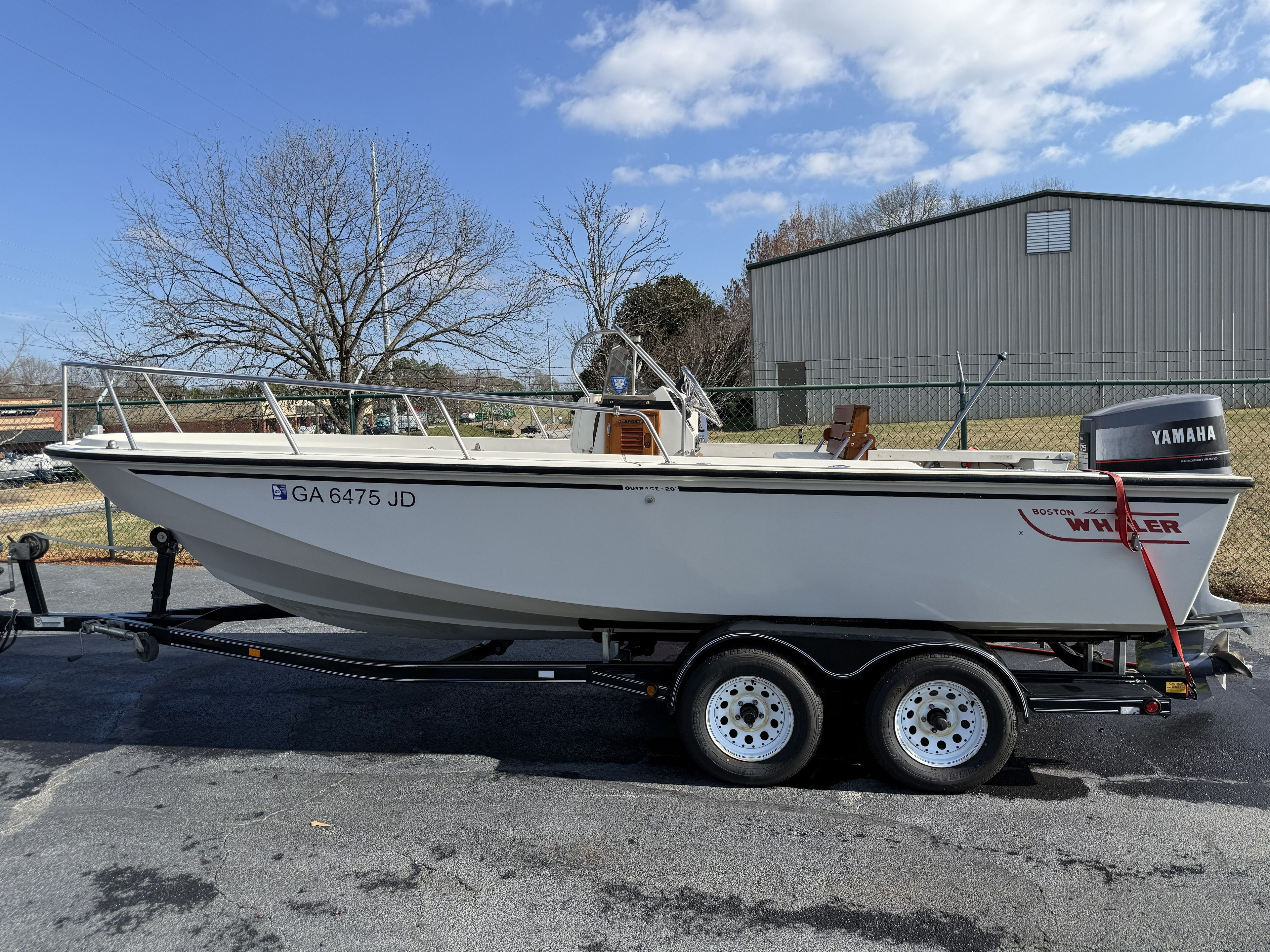 1987 Boston Whaler Outrage V20 on a trailer, with Yamaha outboard motor, parked in front of a building.