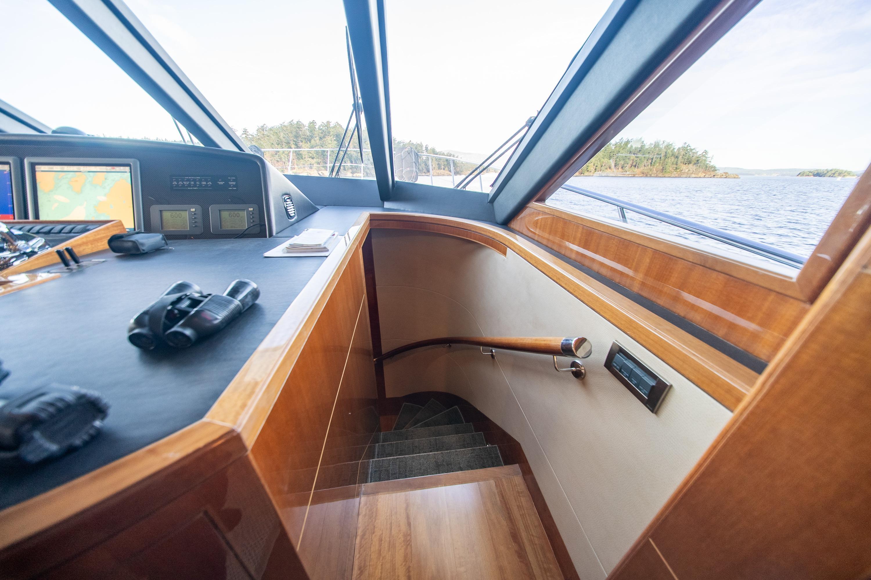 Pilothouse interior of 2007 Ocean Alexander 74, featuring navigation equipment and wooden staircase.