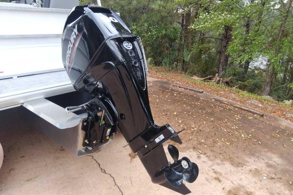 Outboard motor on a 2026 Sun Tracker Party Barge 16 DLX, parked near trees.