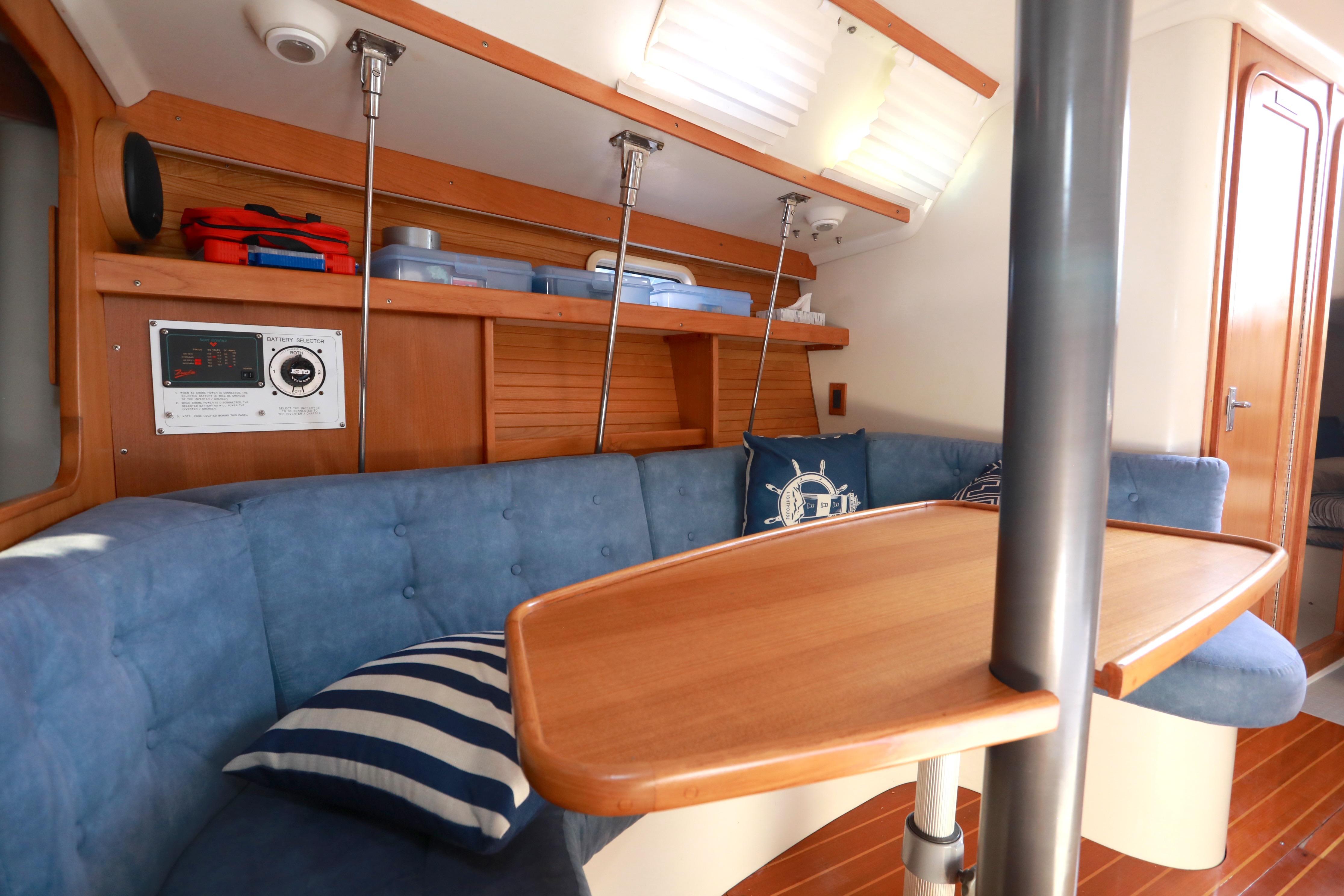 Interior of 1995 Catalina 320 sailboat with blue seating and wooden table.