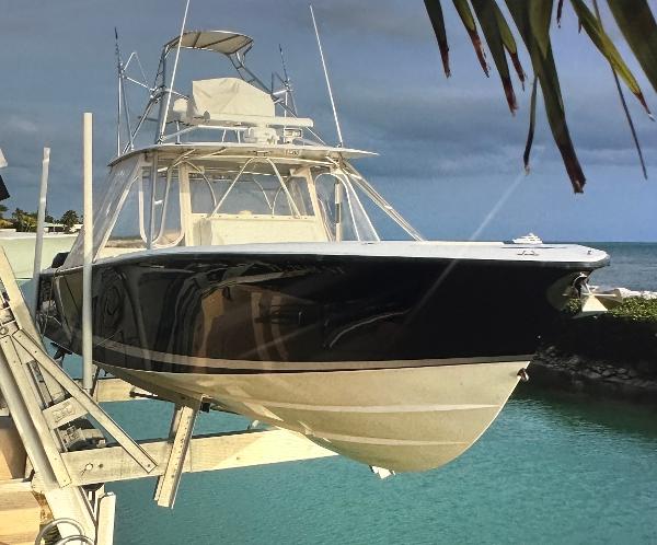 2008 SeaVee 390B boat on lift, docked by turquoise water, under cloudy sky.