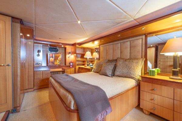 Luxurious master bedroom on a 2001 Grand Harbour 76 yacht with elegant wooden furnishings.