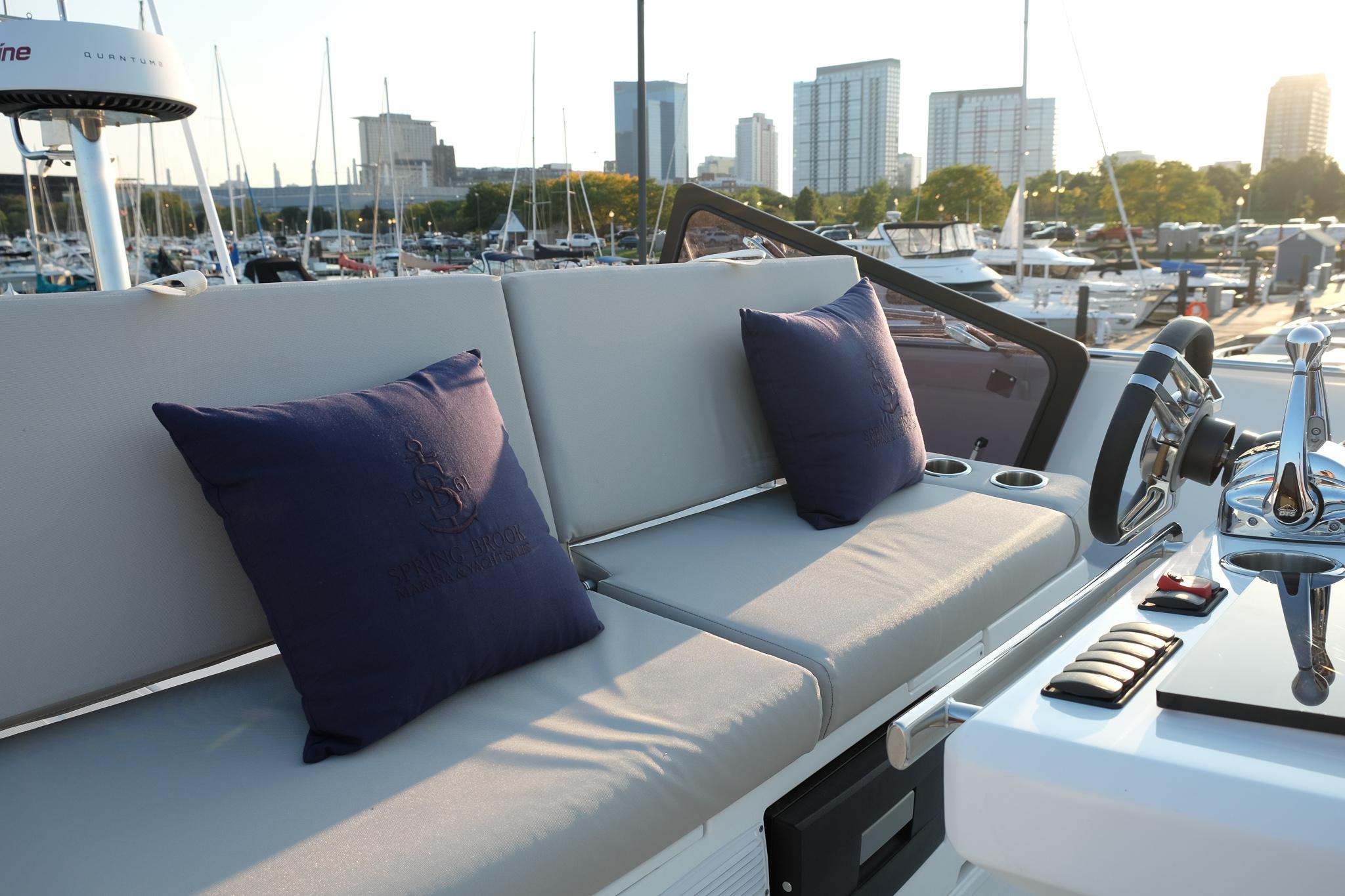 Luxurious seating on 2021 Prestige 590 Sport Fly yacht with city skyline backdrop.