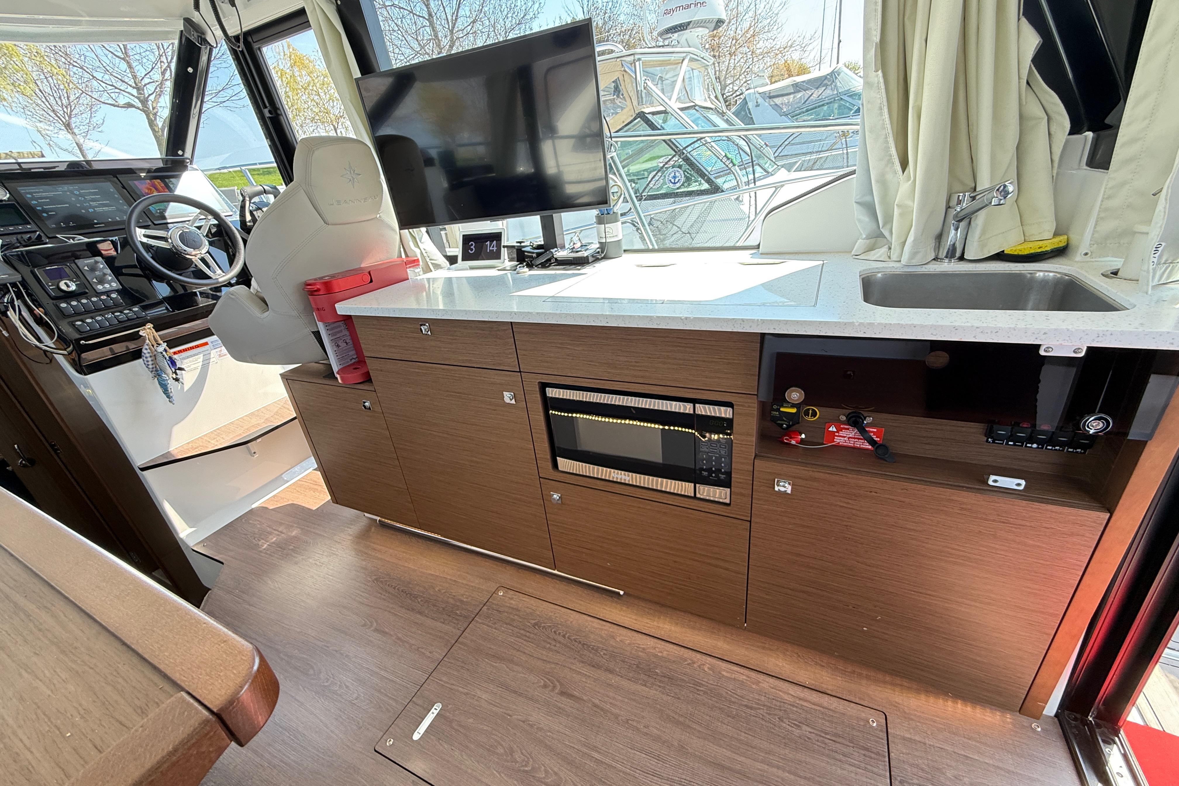 Interior of 2022 Jeanneau NC 1095 Fly boat with helm, kitchenette, and modern amenities.