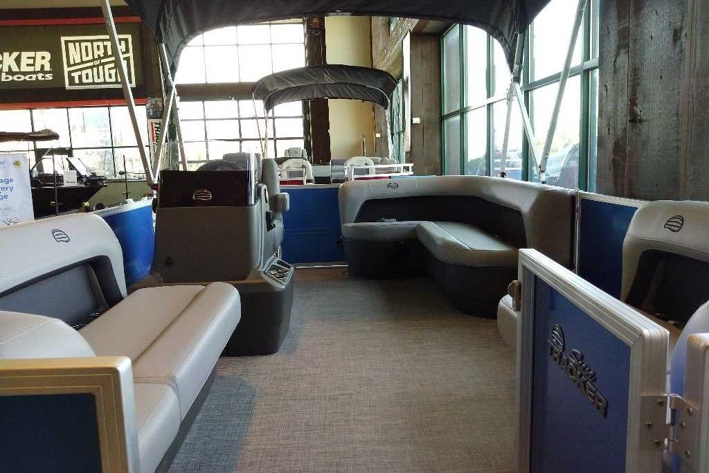 2026 Sun Tracker Party Barge 16 DLX interior with seating and canopy in showroom.