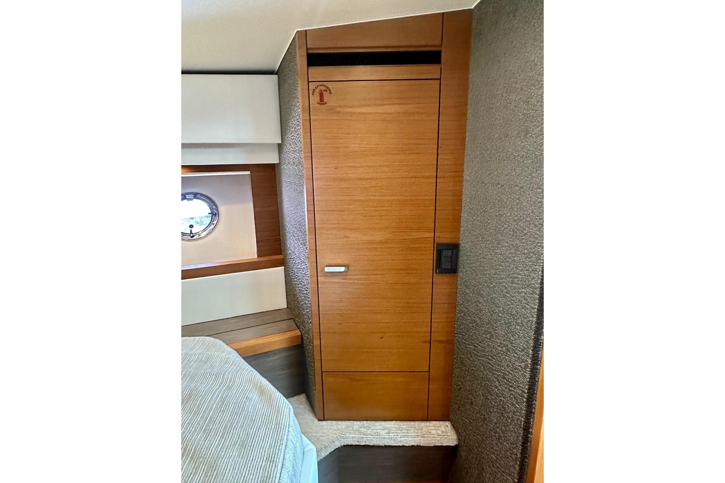 2019 Tiara Yachts F44 Flybridge interior with wooden cabinetry and porthole window.