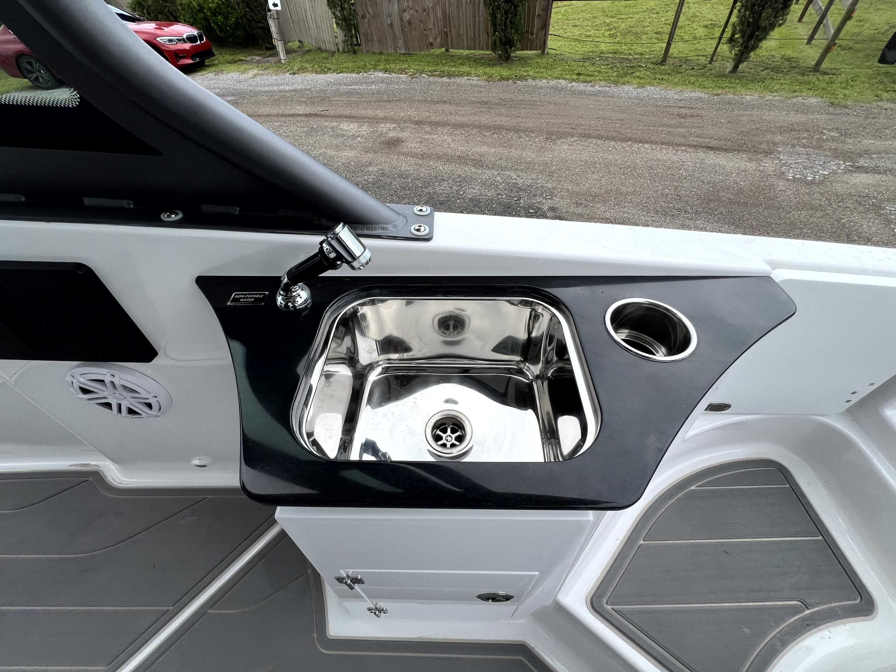 A sleek stainless steel sink on a boat, surrounded by gray and white surfaces.