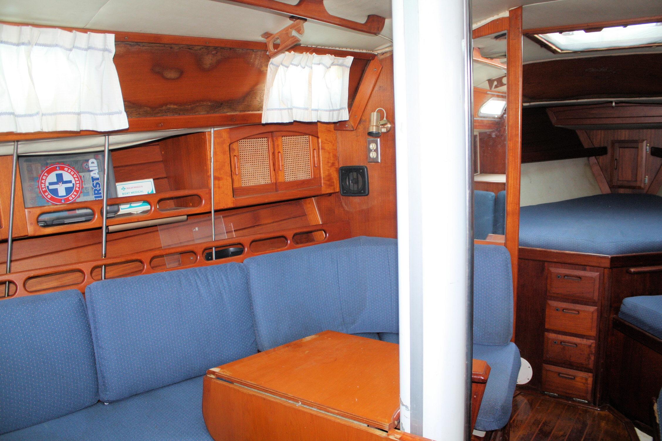 Interior of 1987 Ericson 38-200 sailboat with blue seating and wooden cabinetry.