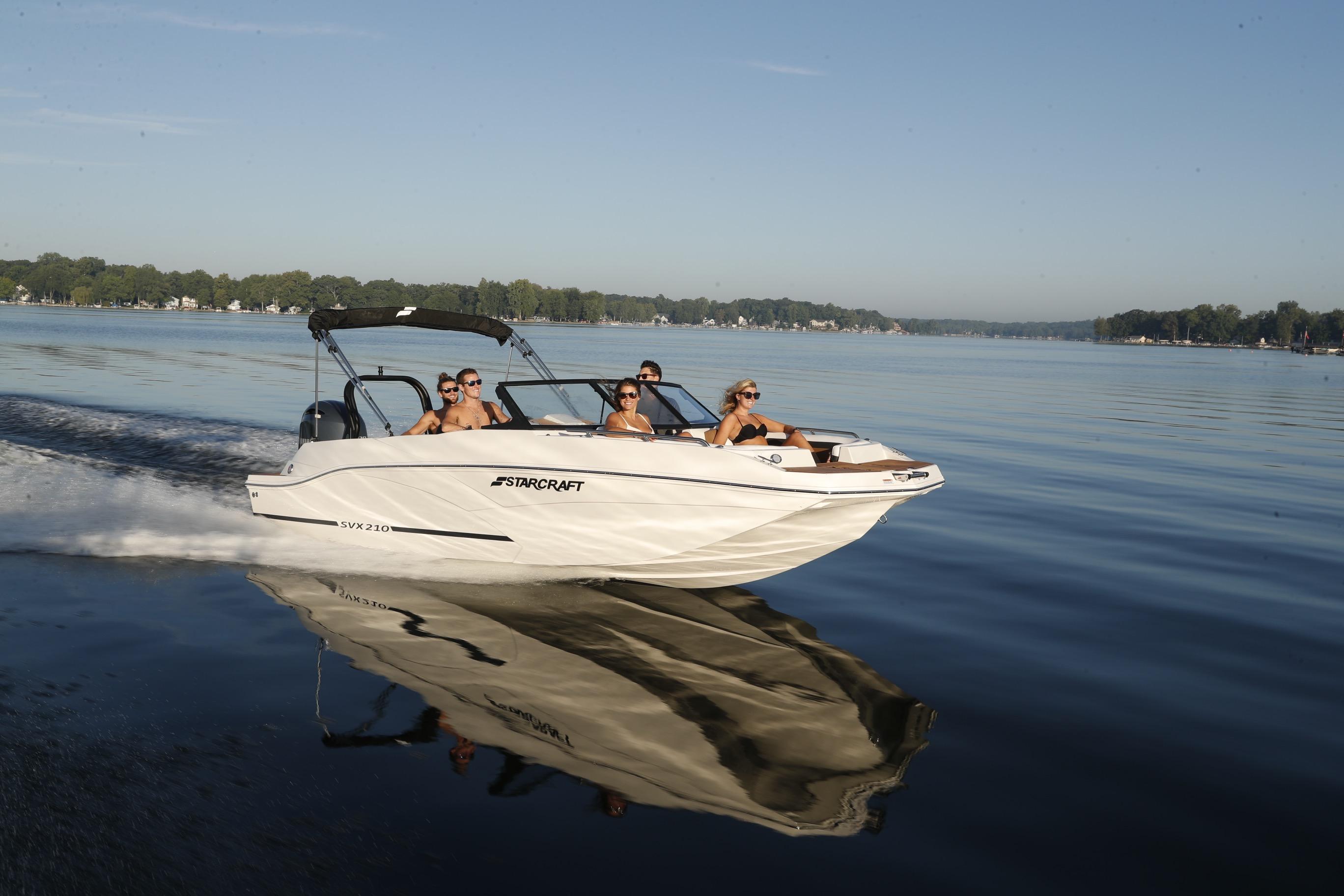 2026 Starcraft SVX 210 DC OB boat cruising on a serene lake with passengers.