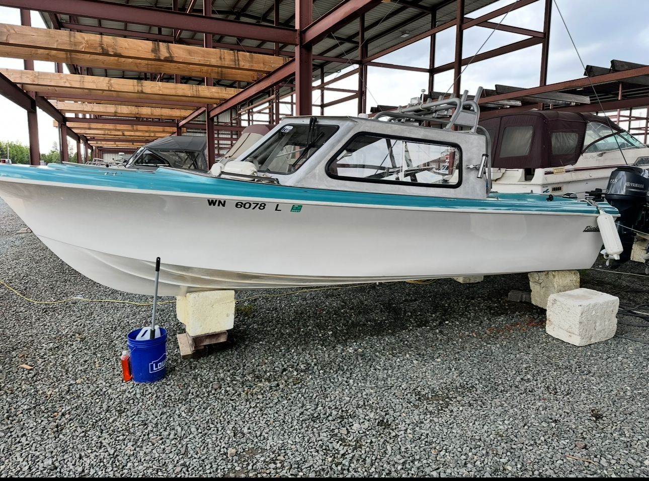 A restored 1967 Fiberform boat sits on blocks in a covered area.
