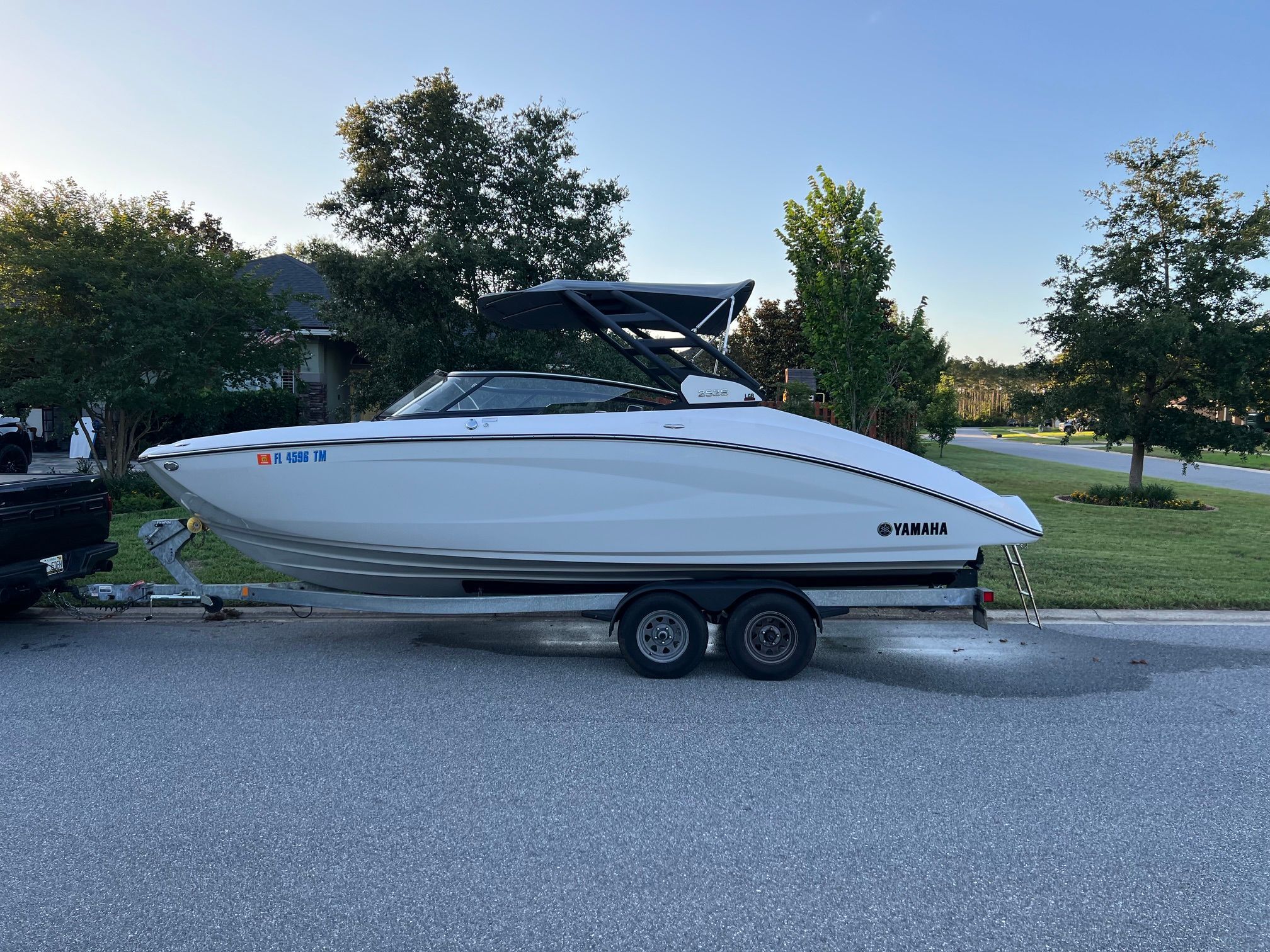 A 2023 Yamaha 252S boat on a trailer in a residential area.