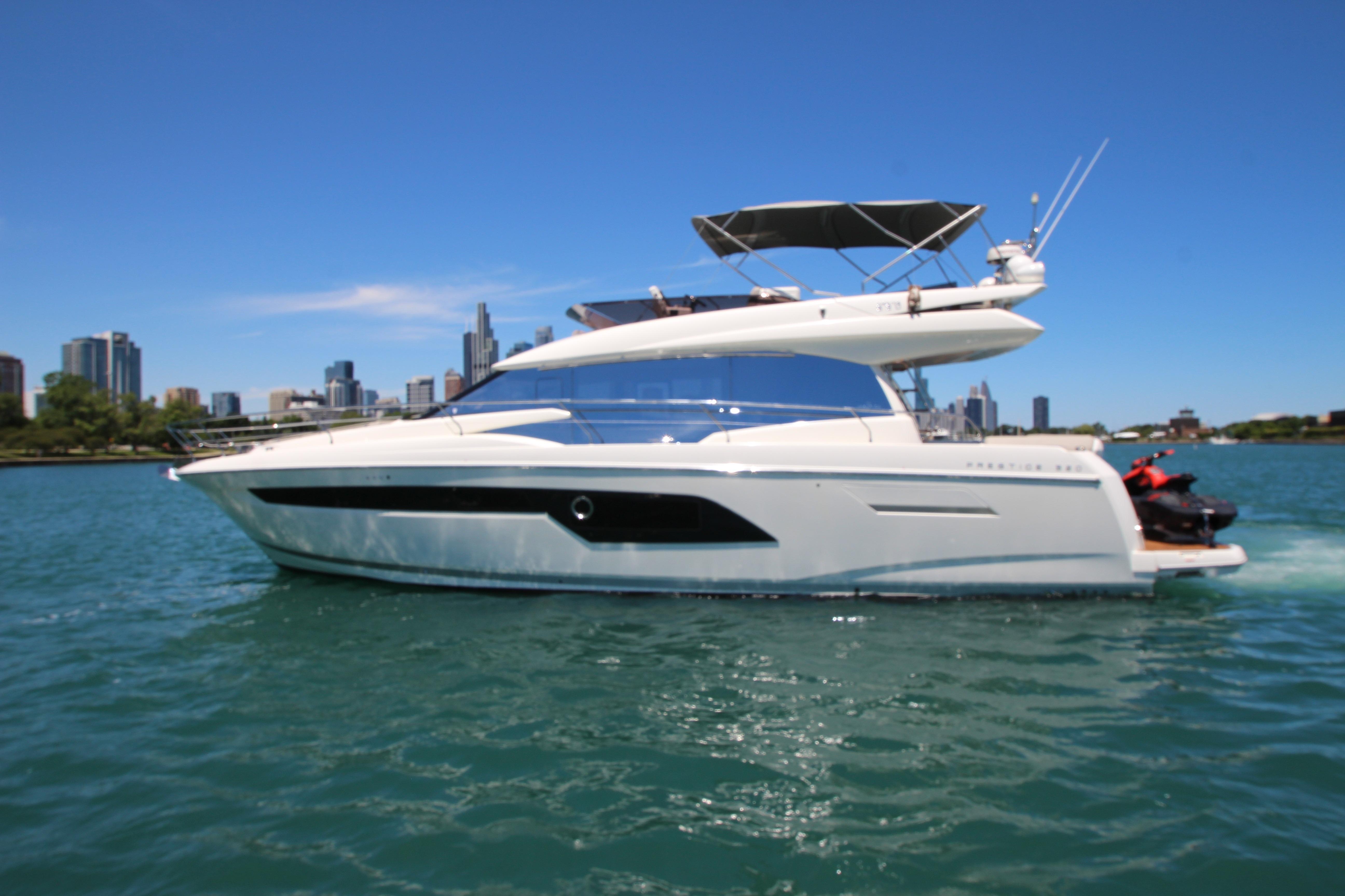 2022 Prestige 520 yacht cruising on a sunny day with city skyline in the background.