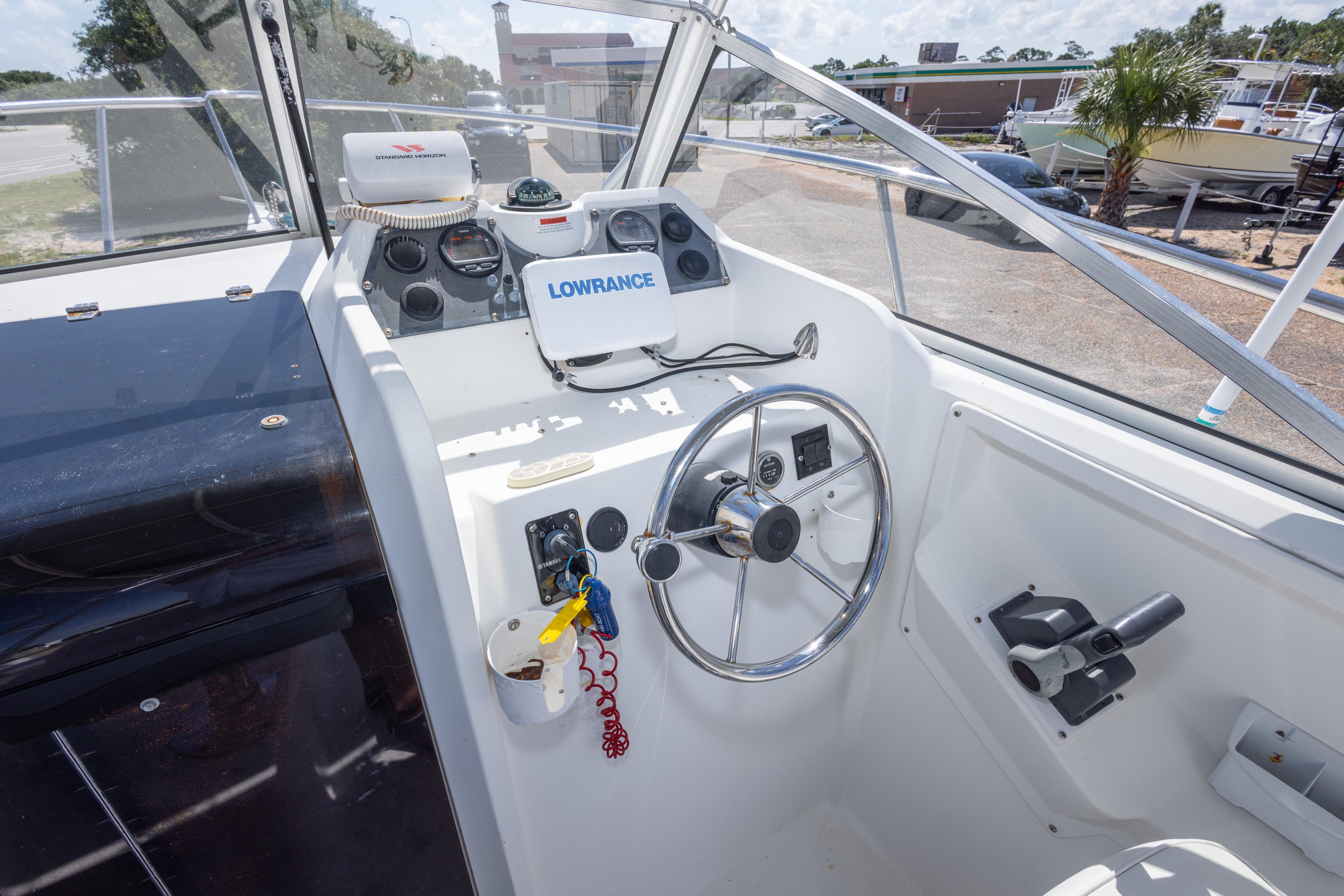 1999 Aquasport 225 Explorer boat cockpit with steering wheel and navigation equipment.