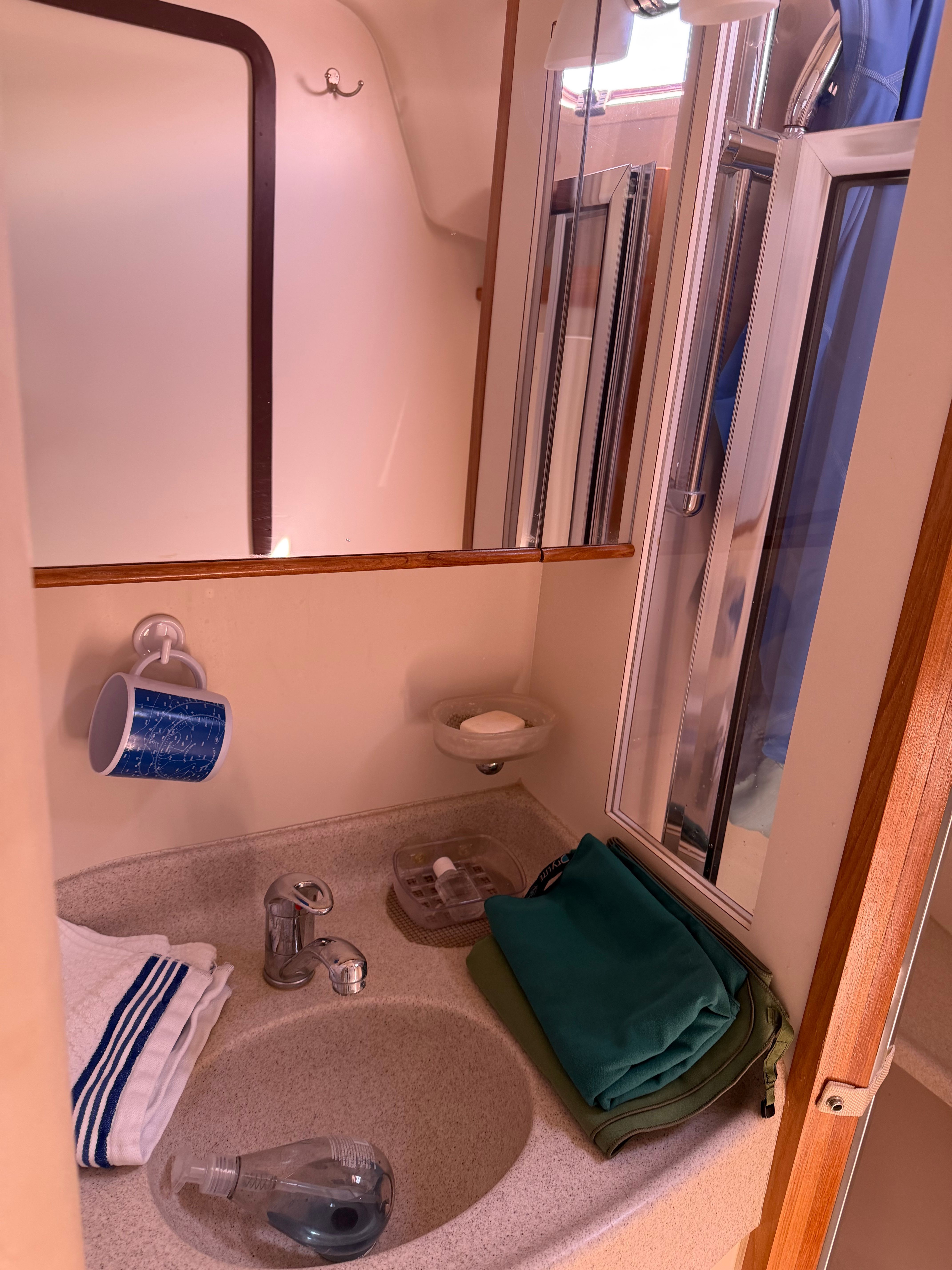 A boat bathroom with a sink, mirror, and towels.