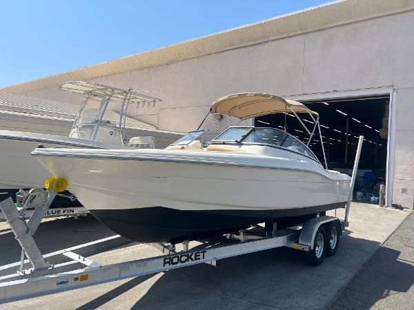 2019 Scout 210 Dorado boat on a trailer outside a warehouse.