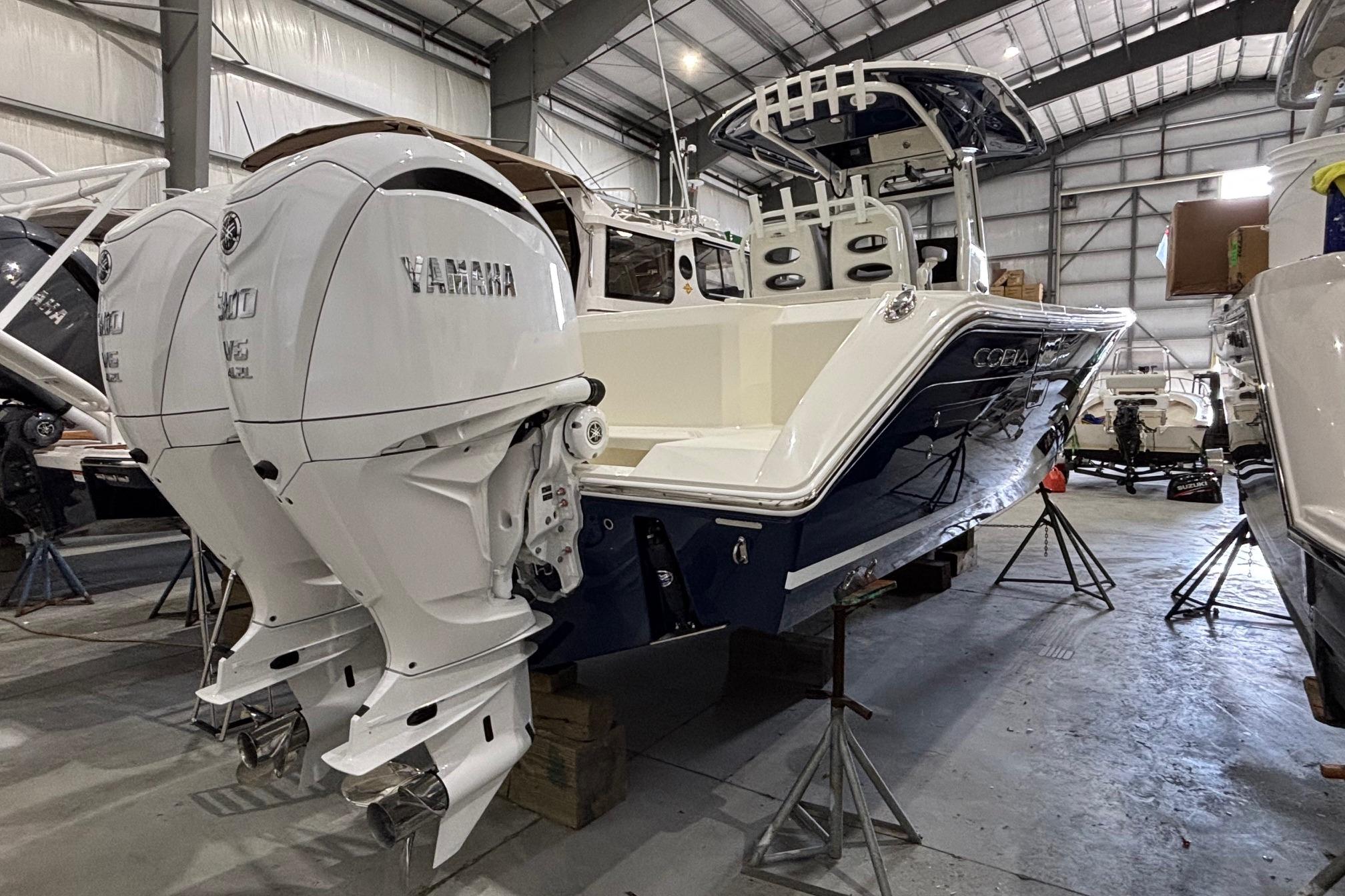 2026 Cobia 285 Open Center Console boat with twin Yamaha engines in a warehouse.