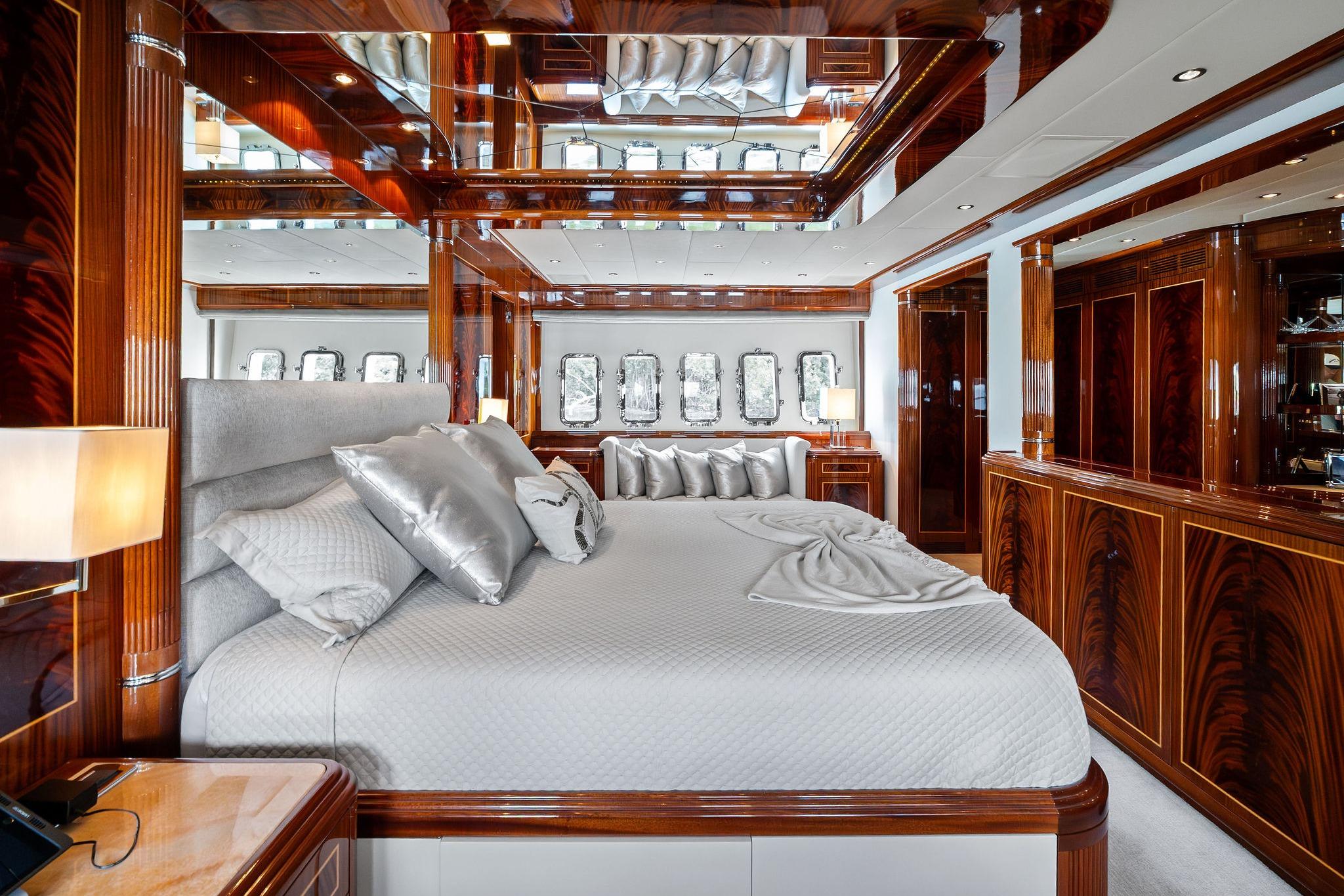 Luxurious bedroom interior on 2005 Mangusta 130 yacht, featuring elegant wood finishes and plush bedding.