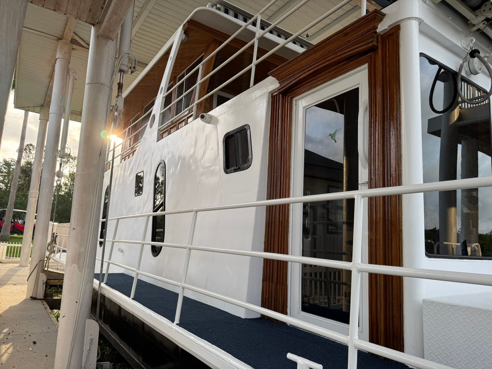 A white boat with wooden accents is docked. It features windows and a railing.