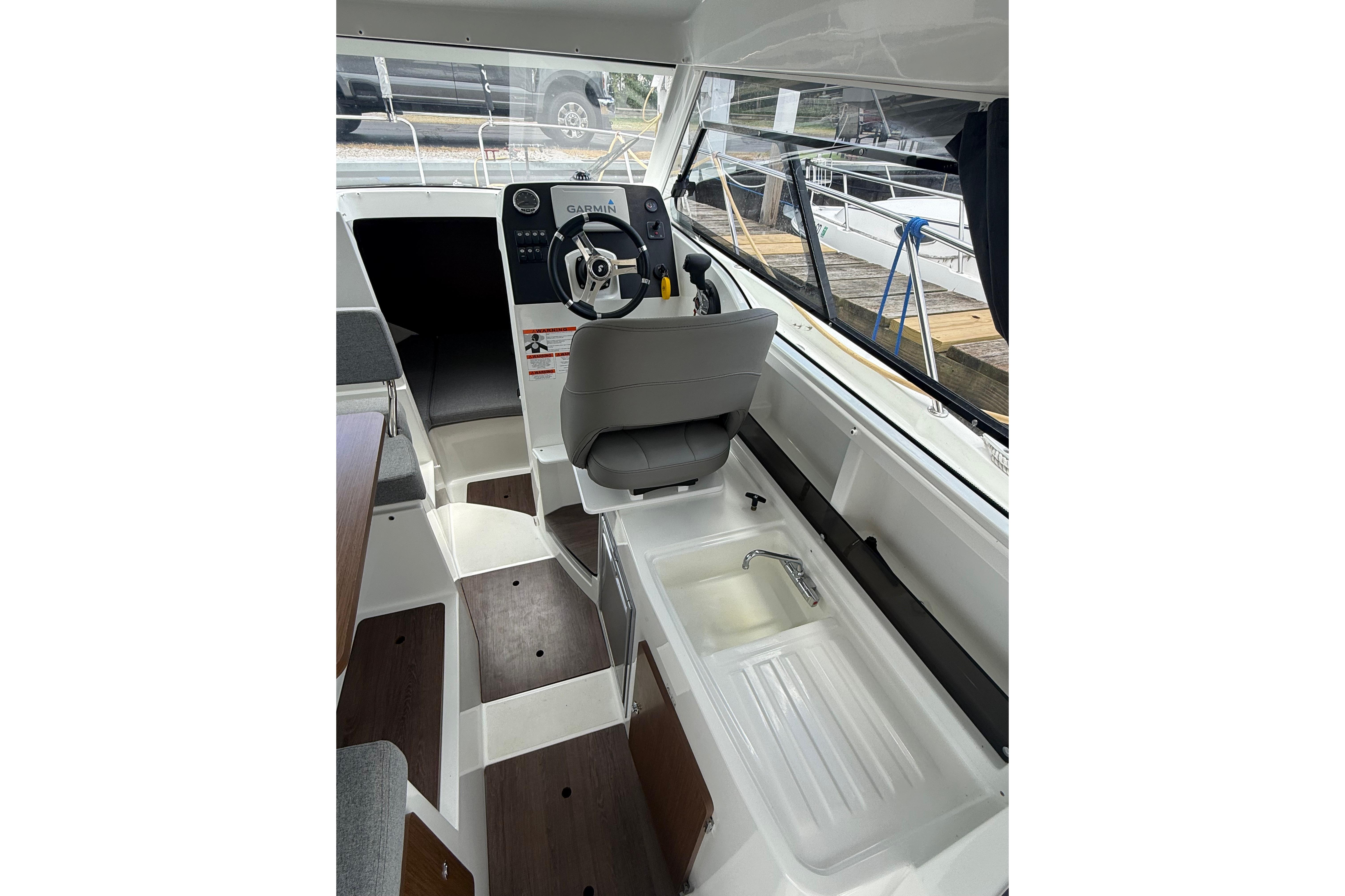 Interior view of 2019 Beneteau Antares 23 boat cockpit with steering wheel and seating.