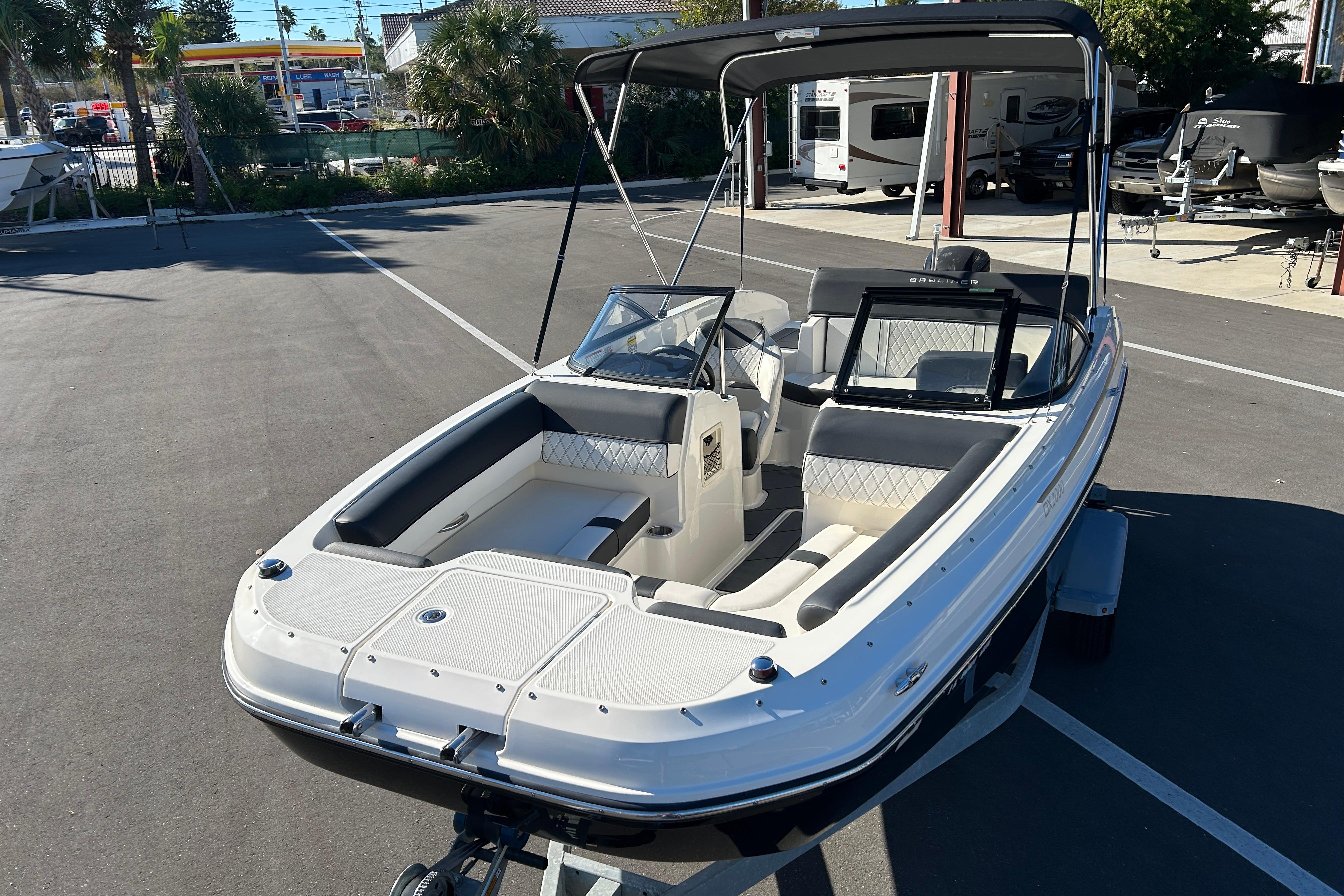 2020 Bayliner DX 2000 boat with canopy, parked on a trailer in a sunny lot.
