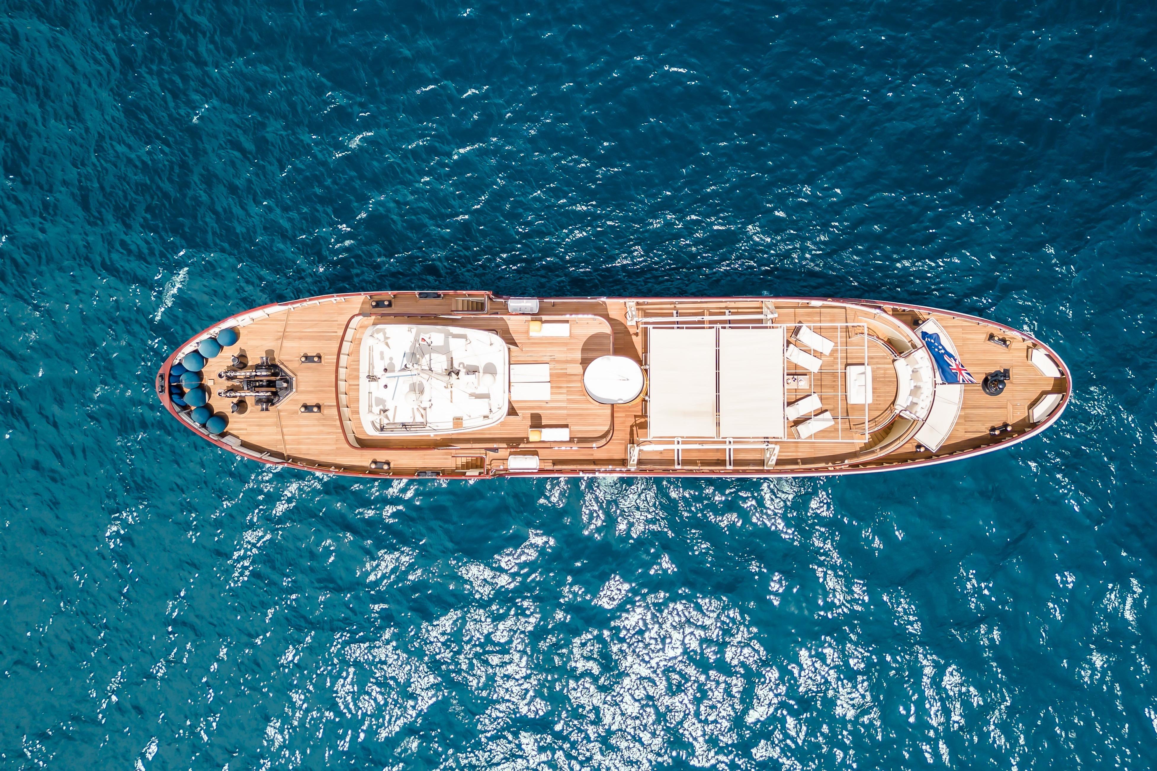 Aerial view of a 1956 custom converted tugboat on blue ocean water.