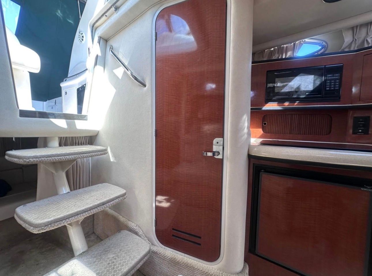 Interior of a 2002 Sea Ray 300 Sundancer with stairs, wooden door, and kitchenette.