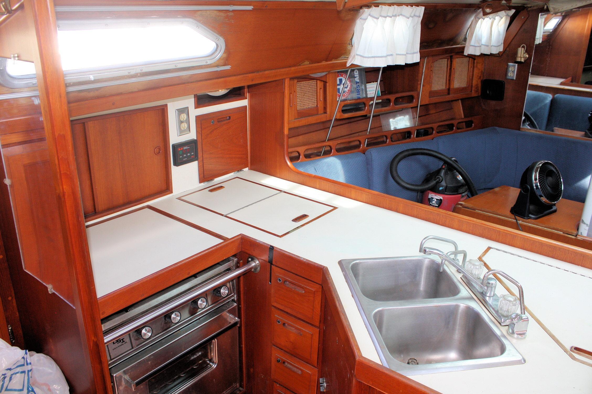 1987 Ericson 38-200 yacht interior with wooden cabinetry, dual sink, and compact kitchen area.