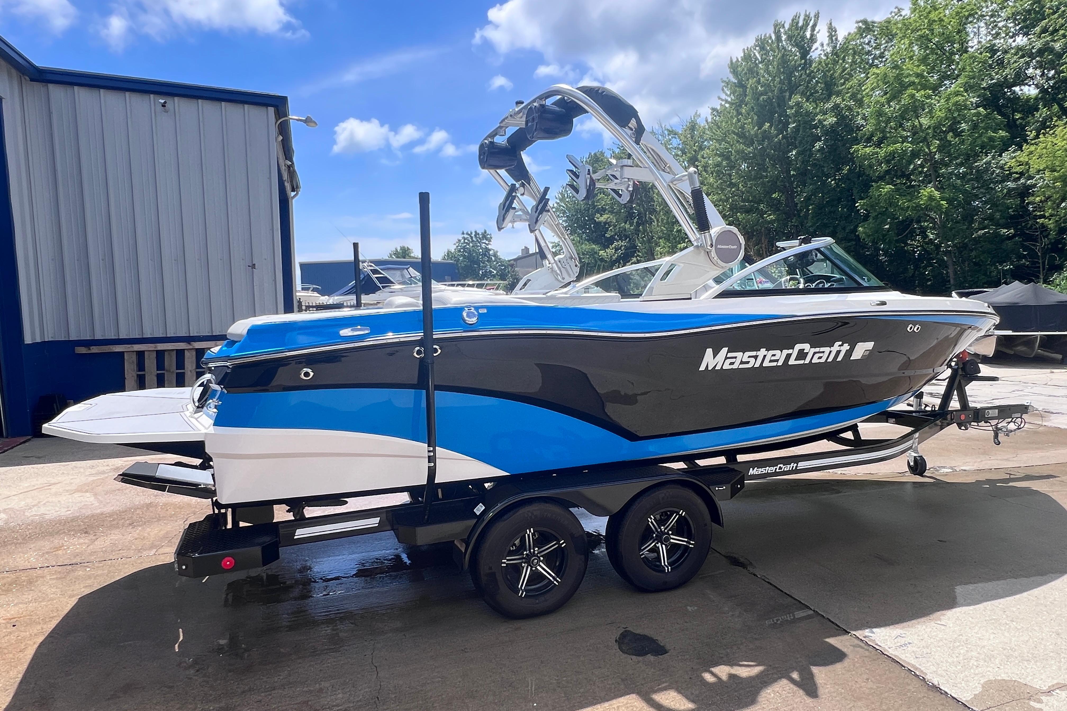 2021 MasterCraft XT23 boat on trailer, blue and black design, parked outdoors.