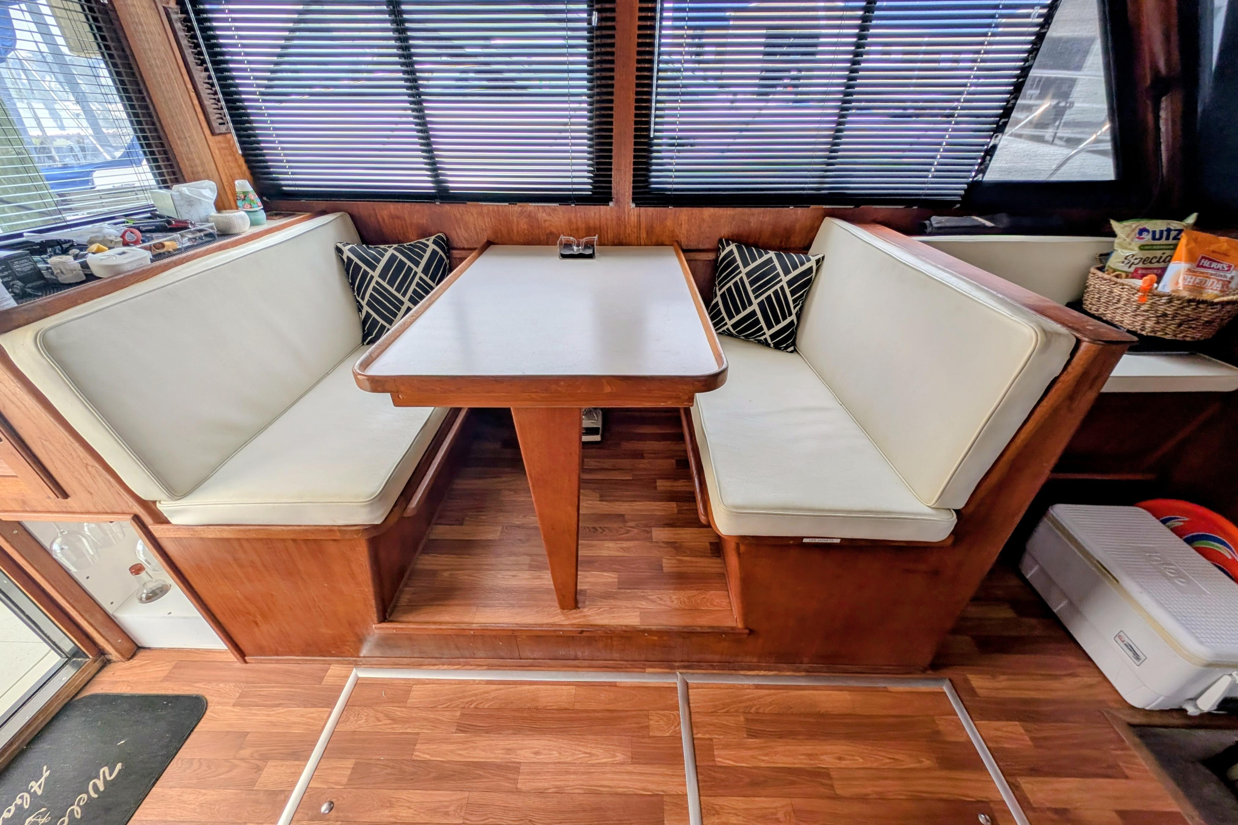 Cozy dining area in a 1998 Markley 46 boat with cushioned seating and wooden accents.