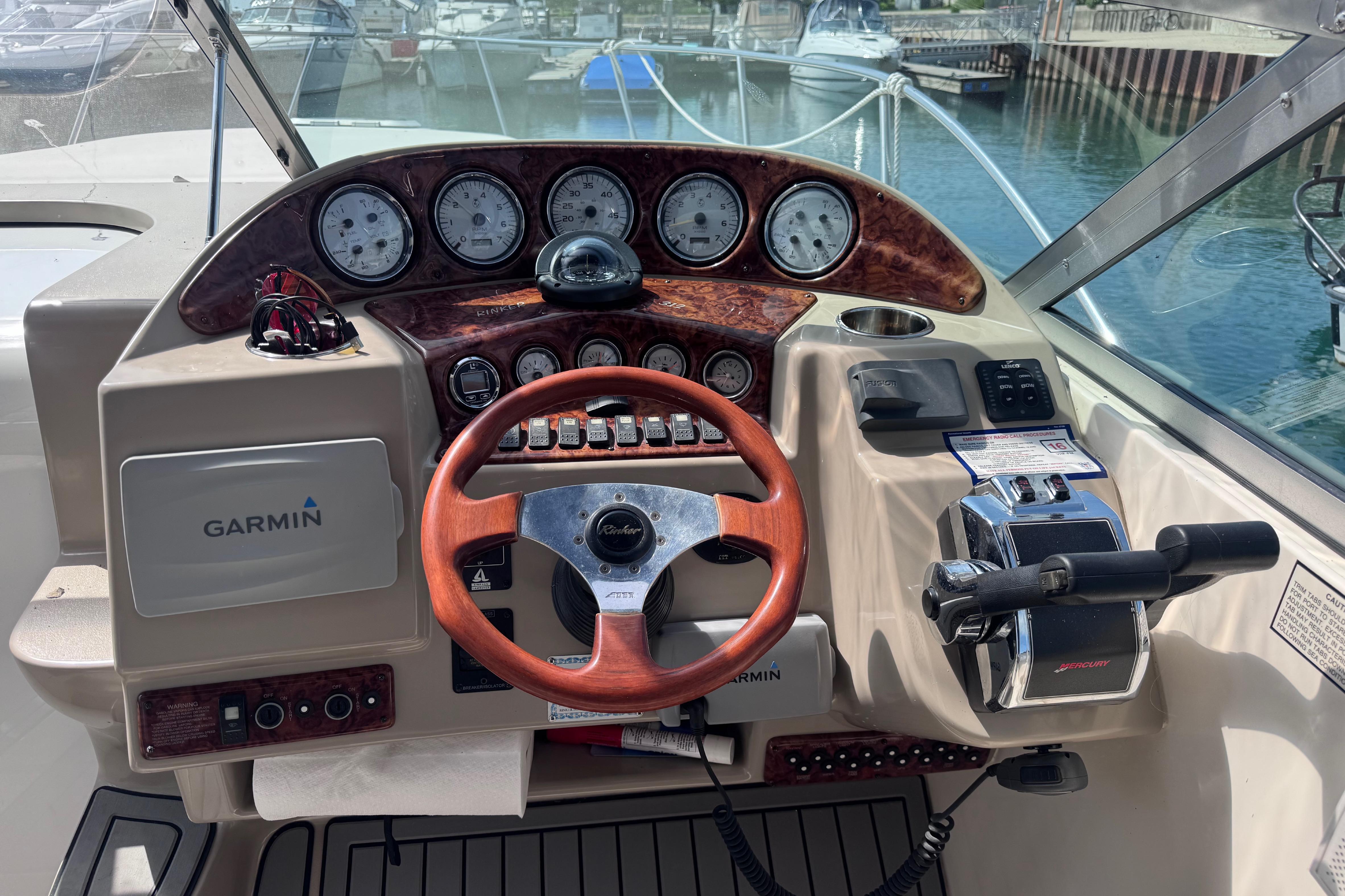 Cockpit of 2003 Rinker Fiesta Vee 312 with Garmin navigation and wood-accented steering wheel.