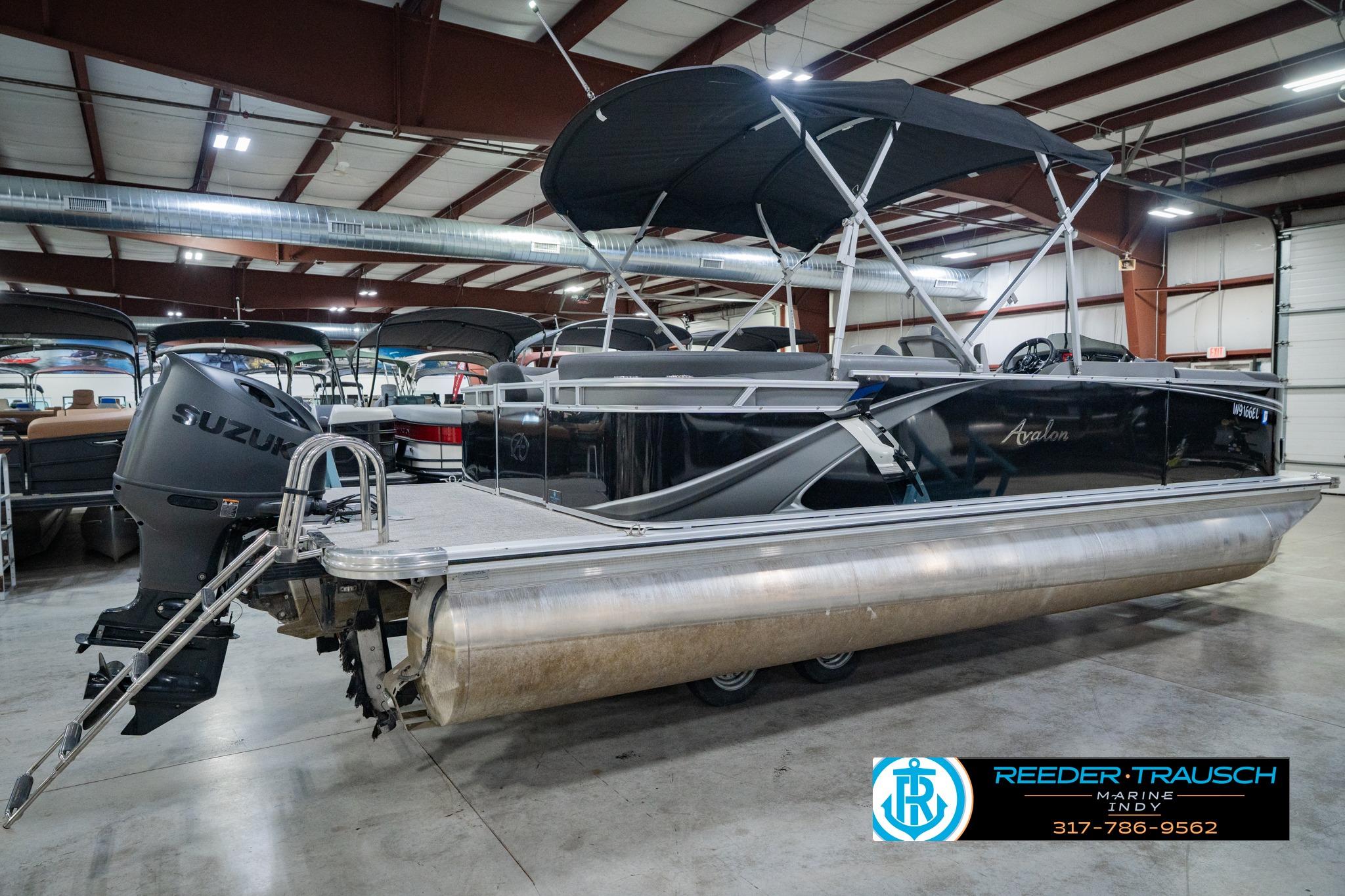 2025 Avalon 2385 LSZ ENT pontoon boat in showroom with Suzuki outboard motor.