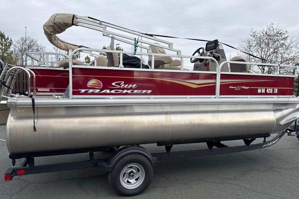 2024 Sun Tracker Bass Buggy 18 DLX pontoon boat on trailer, side view.