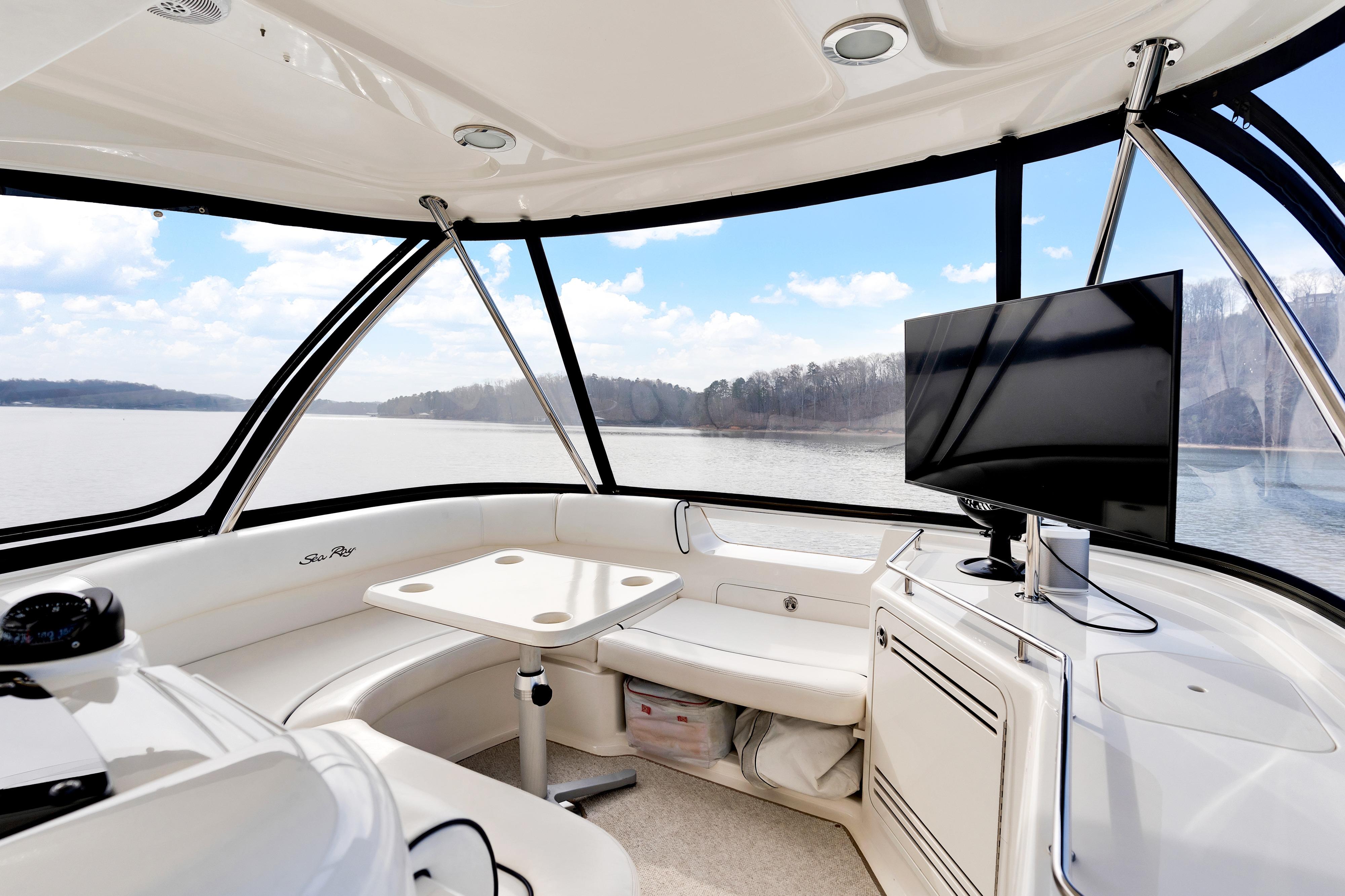 Interior of 2006 Sea Ray 58 Sedan Bridge yacht with seating and TV, overlooking serene water.