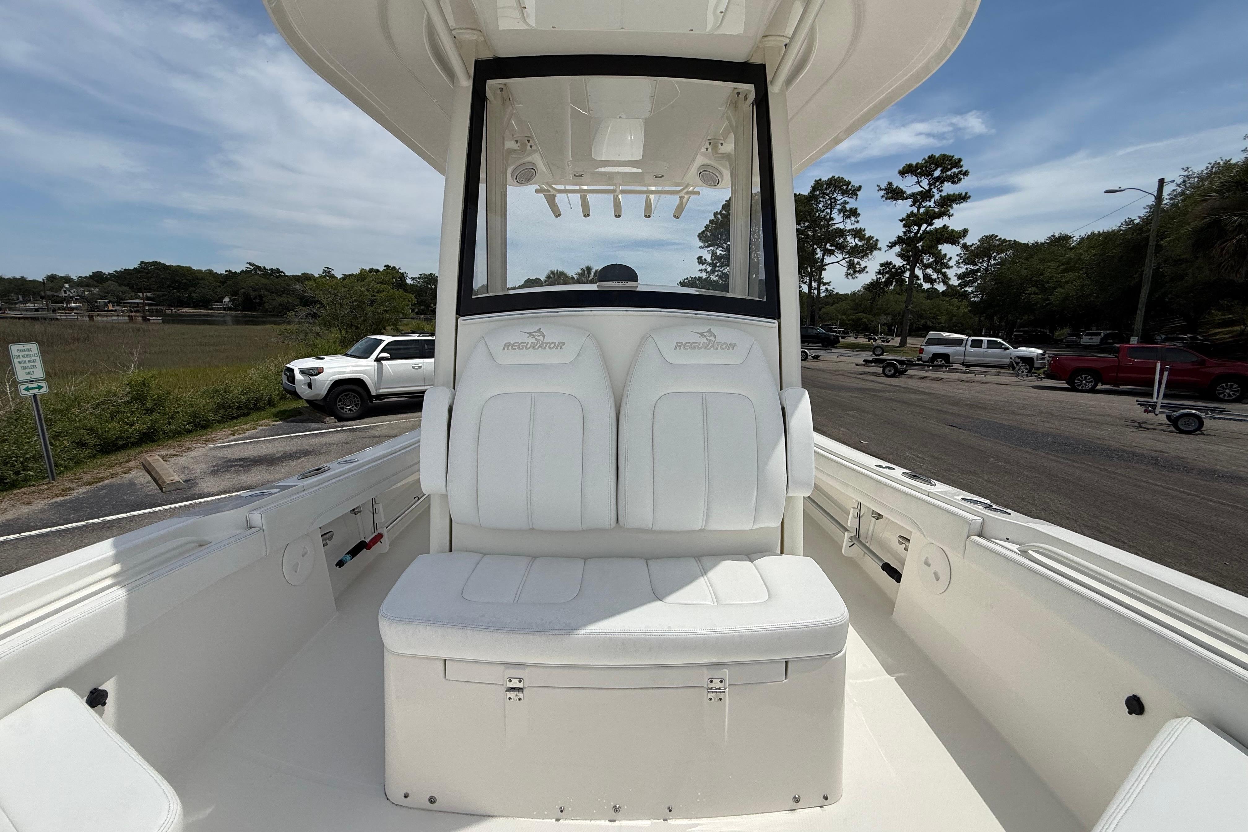 2019 Regulator 26XO boat interior with white seating and console, parked near a scenic area.
