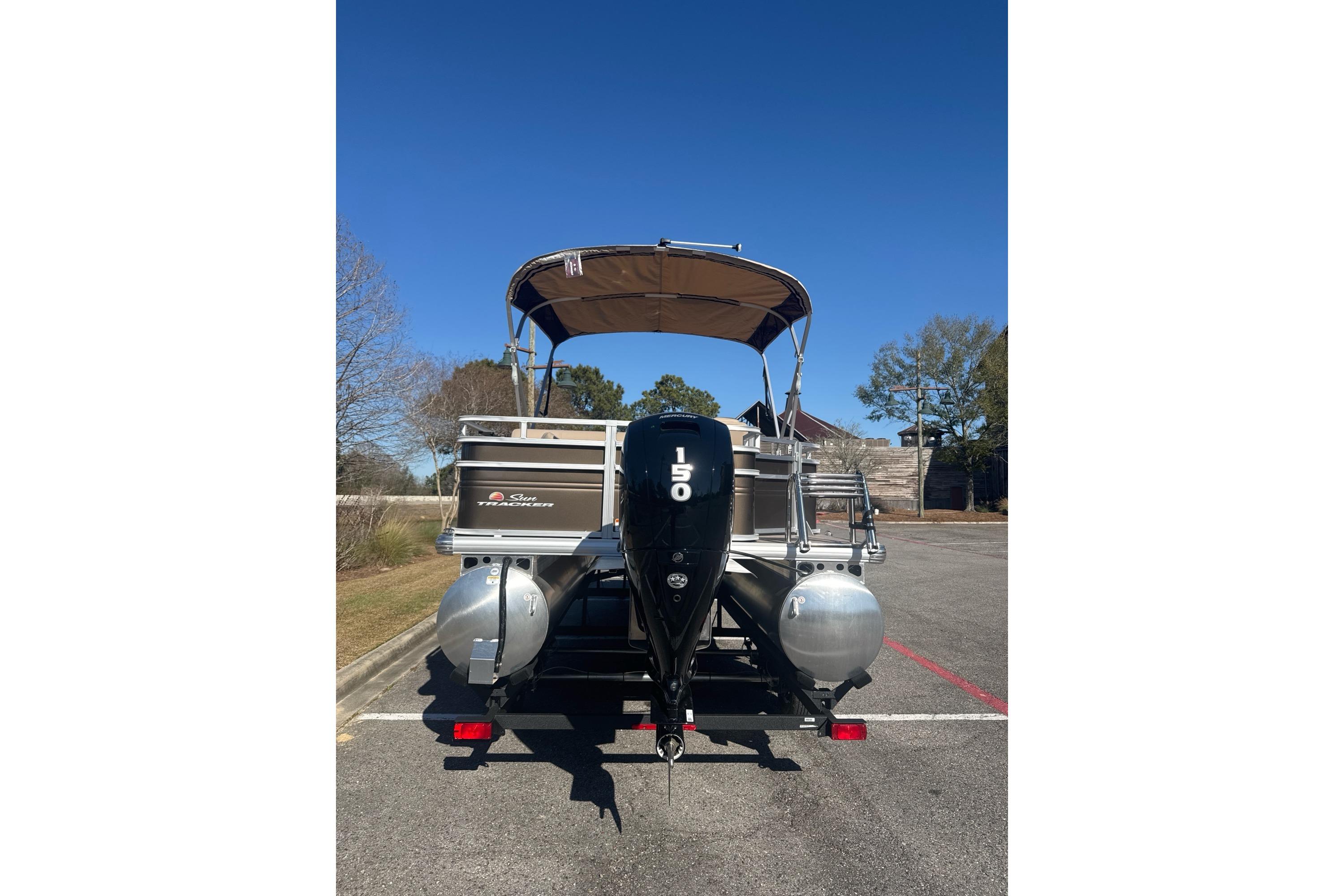 2025 Sun Tracker SportFish 22 DLX pontoon boat with outboard motor, parked outdoors.