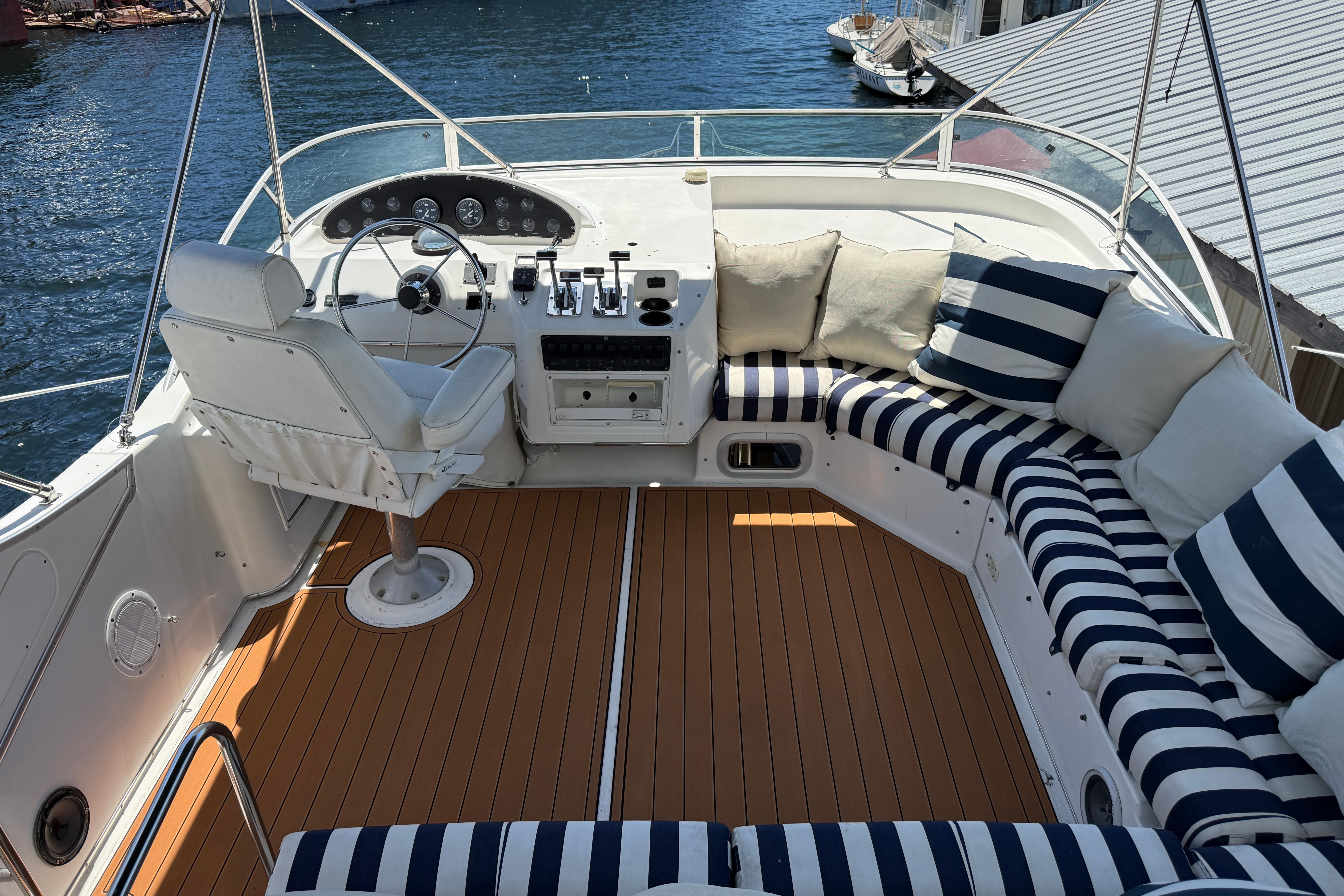1997 Bayliner 3988 Command Bridge Motoryacht with striped seating and helm, docked by the water.