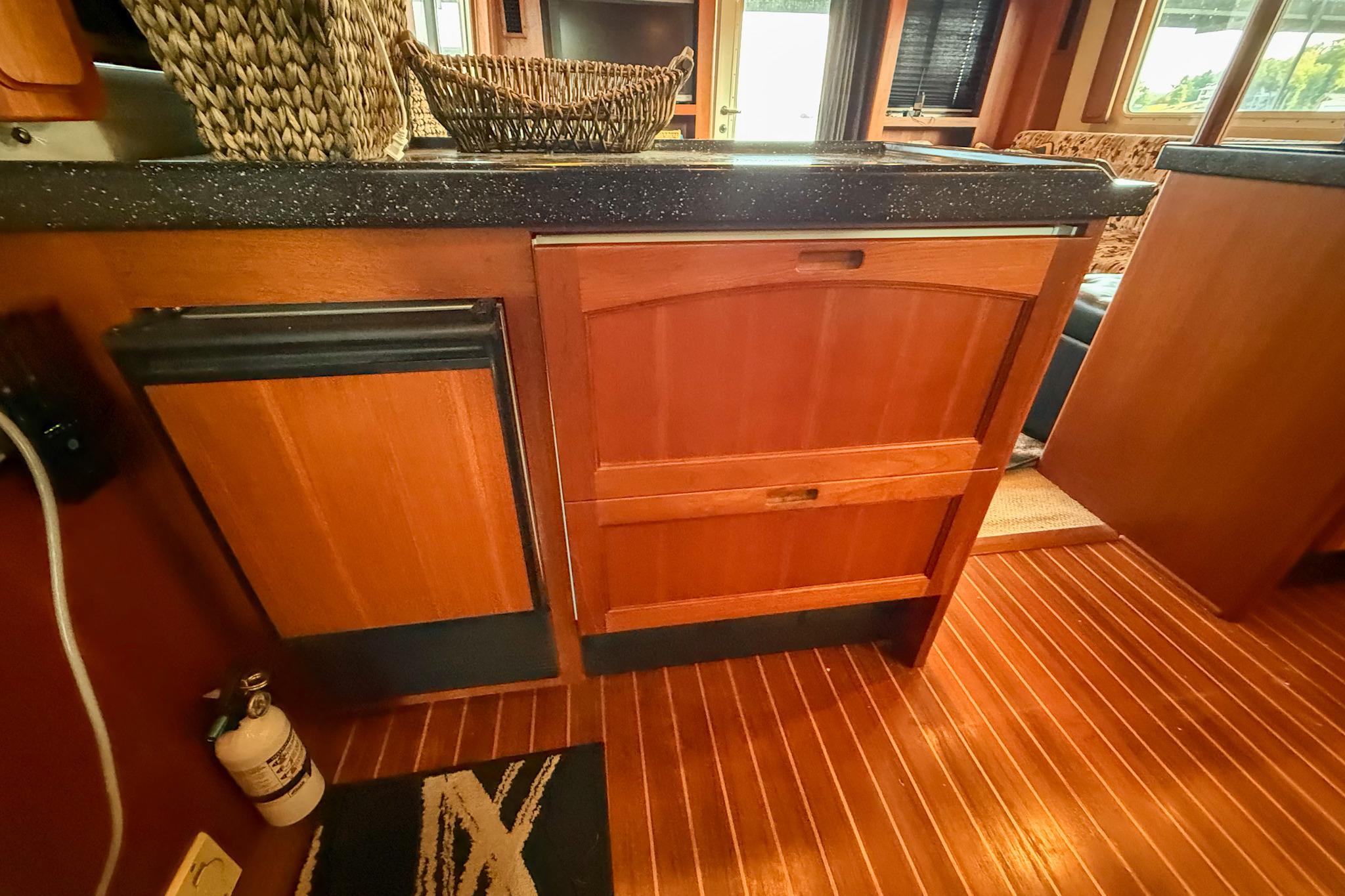 Wooden cabinetry and flooring in 2007 Nordic Tug 54 interior, featuring woven baskets and countertop.